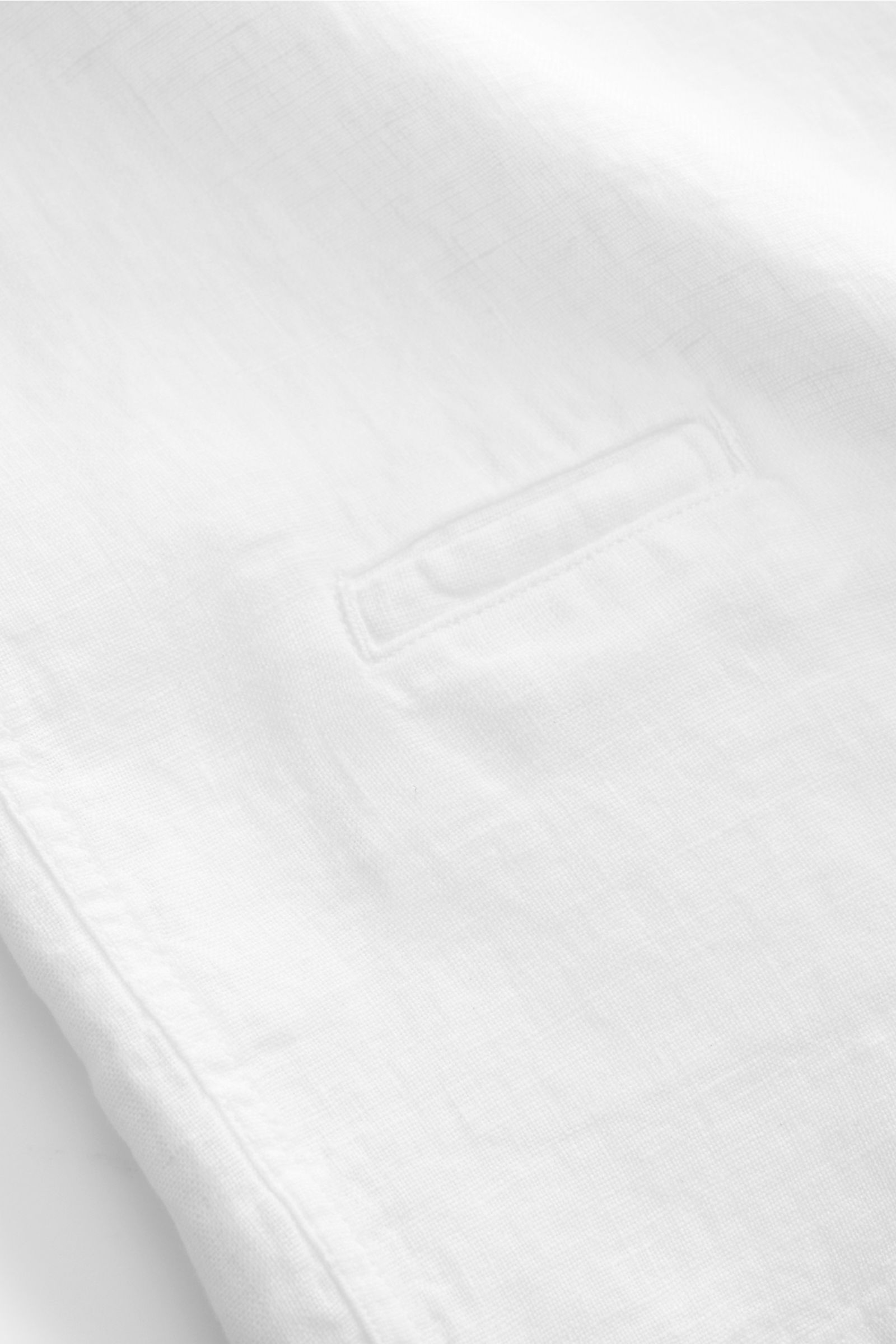 Nahaufnahme des weißen 04651/ A trip in a bag Leinen-Kurzarmhemd Kubanischer Kragen, reine Leinenstruktur, Münztasche, gerader Saum.