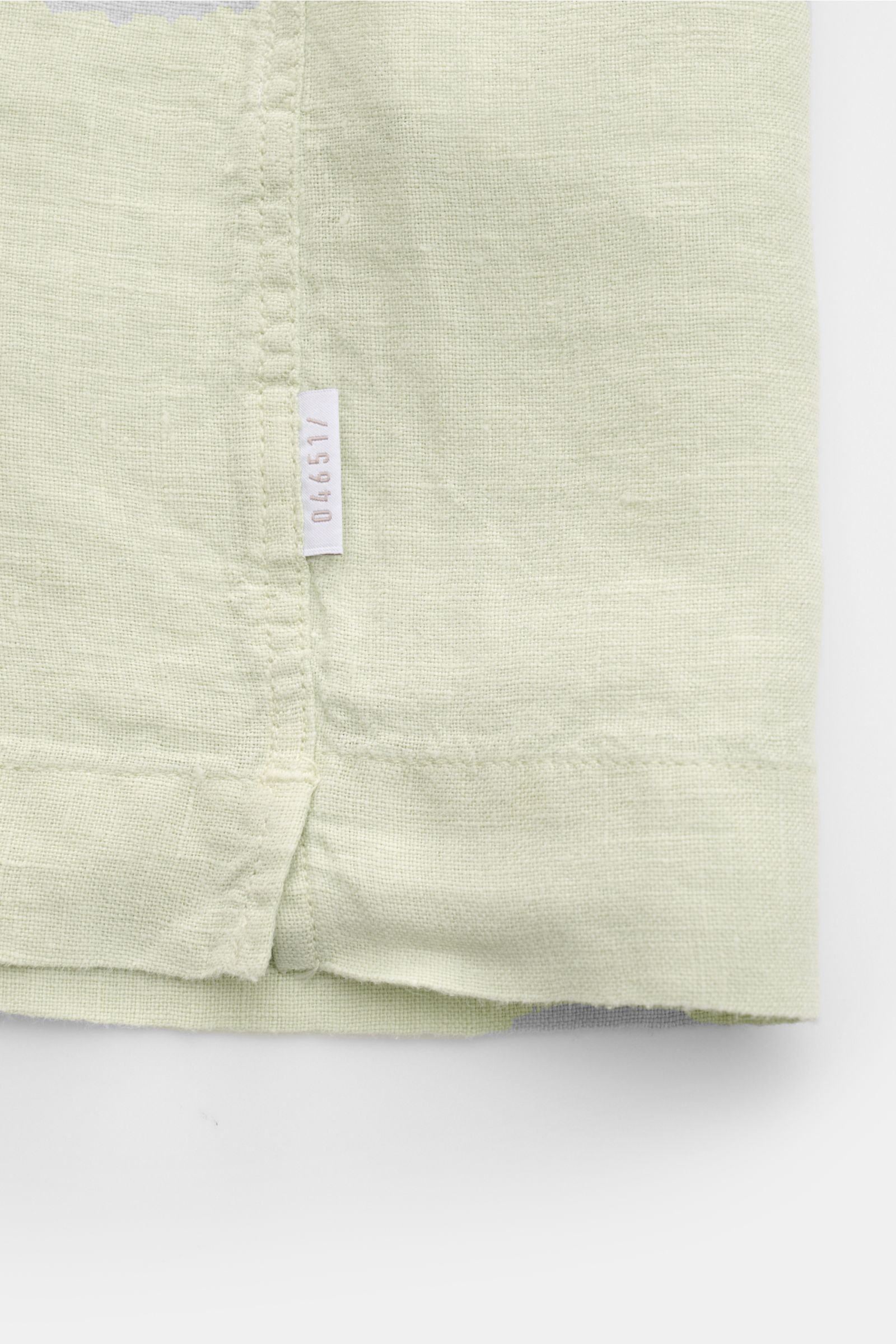 04651/ A trip in a bag Leinen-Kurzarmhemd Kubanischer Kragen pastellgrün, Detailansicht von unten mit Saumschlitzen und Weblabel, reine Leinenstruktur.