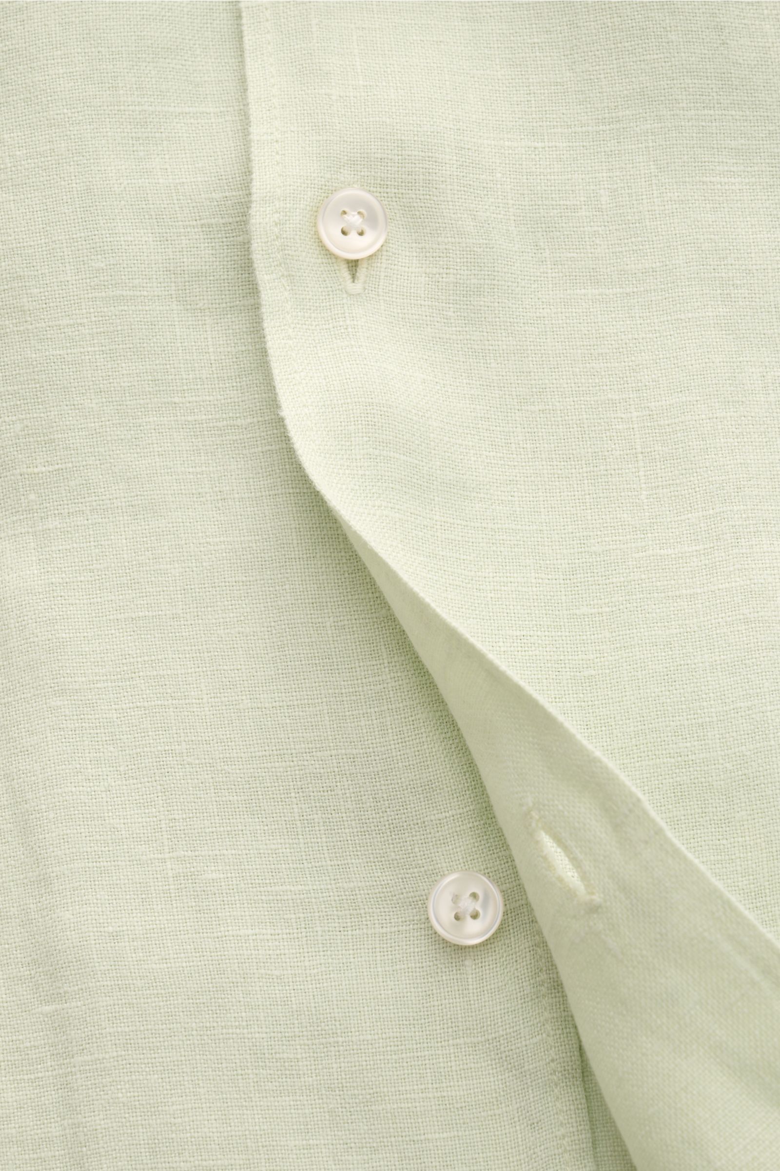 Nahaufnahme des pastellgrünen 04651/ A trip in a bag Leinen-Kurzarmhemd Kubanischer Kragen mit Knöpfen und feiner Leinenstruktur, von schräg oben fotografiert.