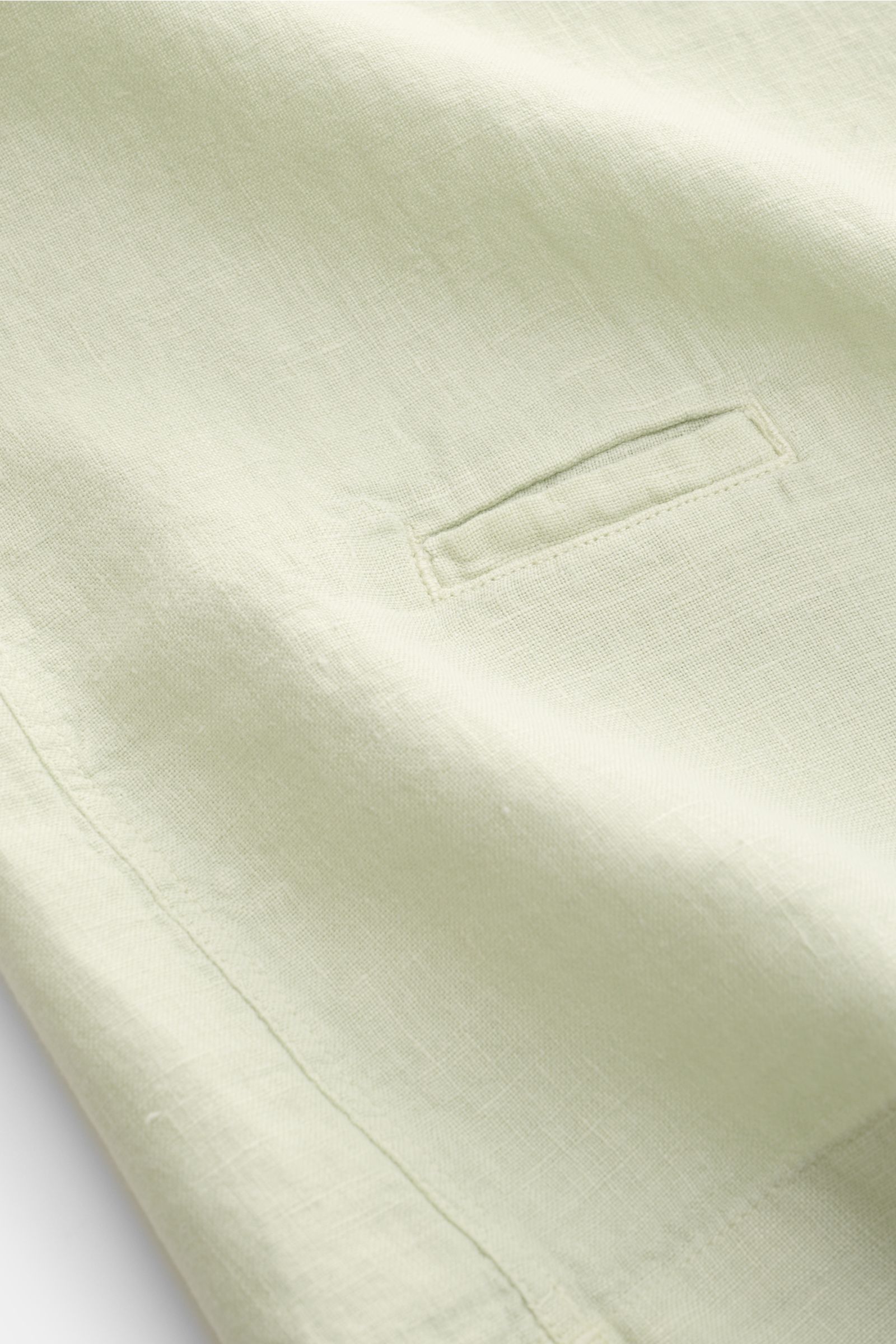 Nahaufnahme des pastellgrünen 04651/ A trip in a bag Leinen-Kurzarmhemd Kubanischer Kragen, Detail der kleinen Münztasche und Leinenstruktur.