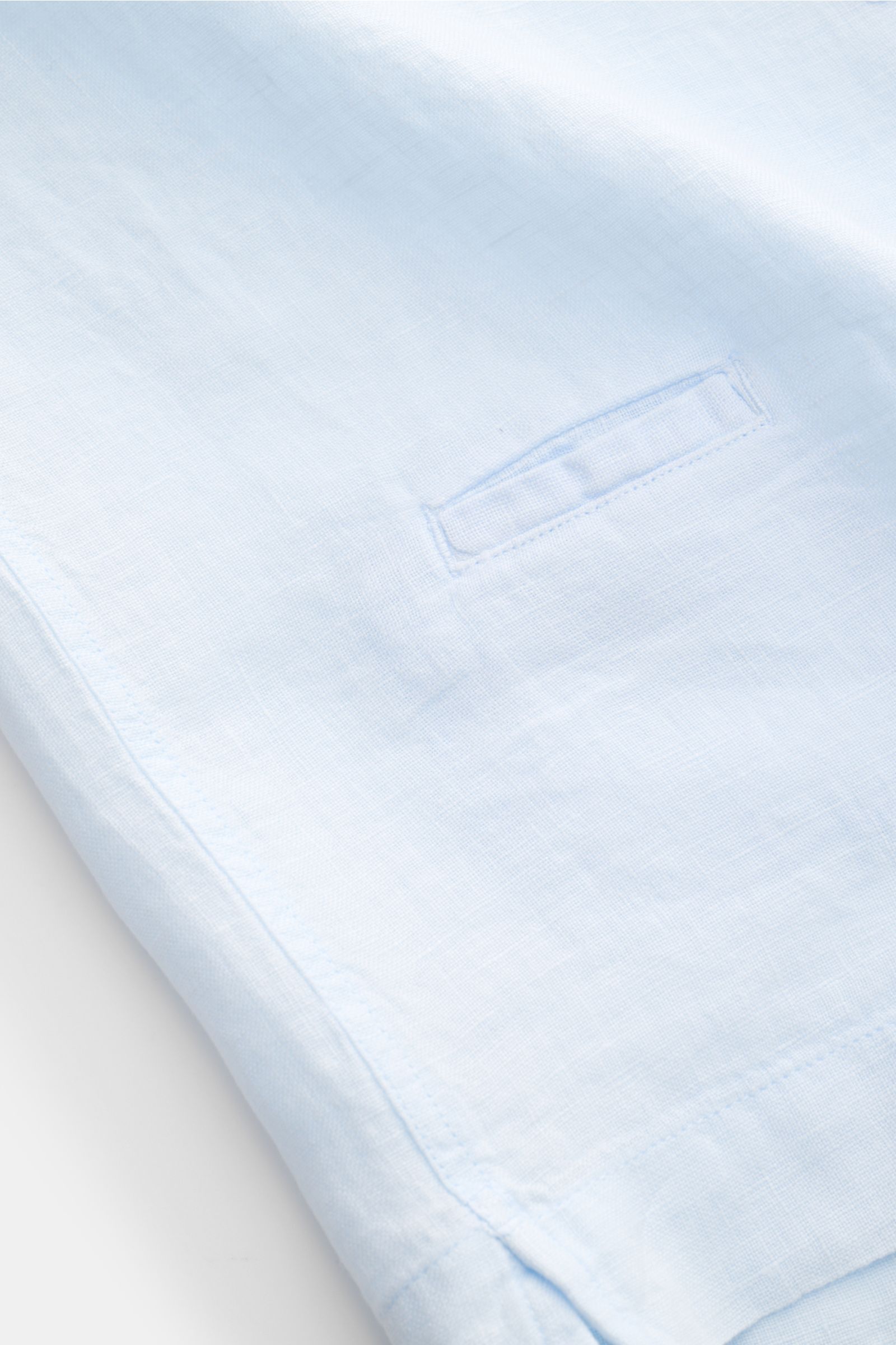 Nahaufnahme des pastellblauen 04651/ A trip in a bag Leinen-Kurzarmhemd Kubanischer Kragen, Details von Saum, Münztasche und leichter Leinenstruktur.