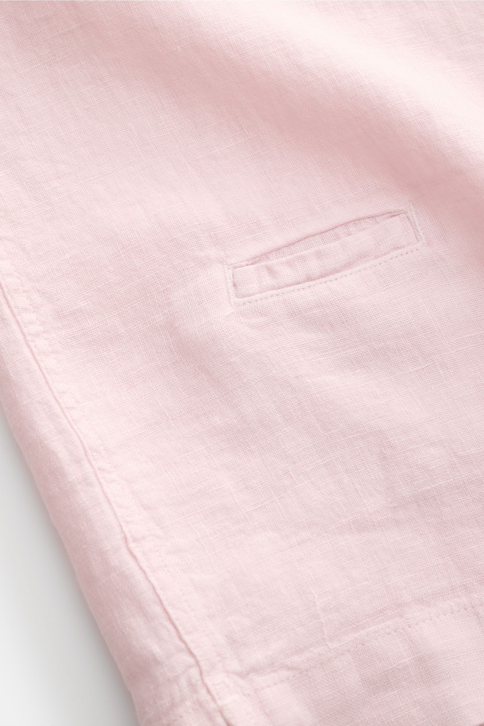 Nahaufnahme eines roséfarbenen 04651/ A trip in a bag Leinen-Kurzarmhemd Kubanischer Kragen, detailreich fotografiert von der Seitennaht mit Münztasche, feiner Leinenstruktur und kurzem Saumschlitz, luftig und leicht für sommerliche Looks.
