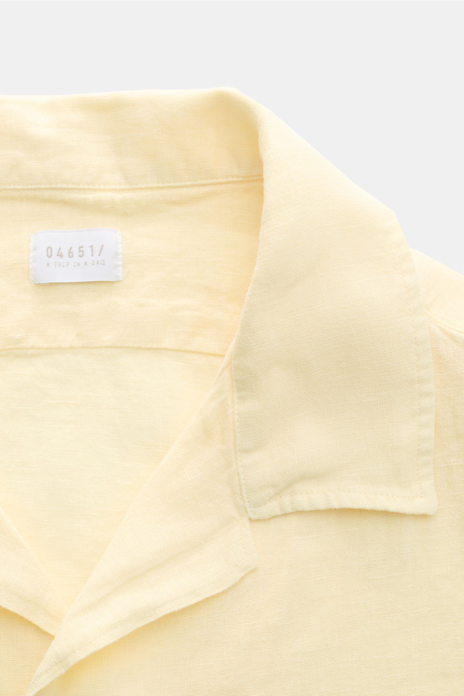 Nahaufnahme des pastellgelben 04651/ A trip in a bag Leinen-Kurzarmhemd Kubanischer Kragen, luftige Struktur, klassischer Kragen, von oben fotografiert.