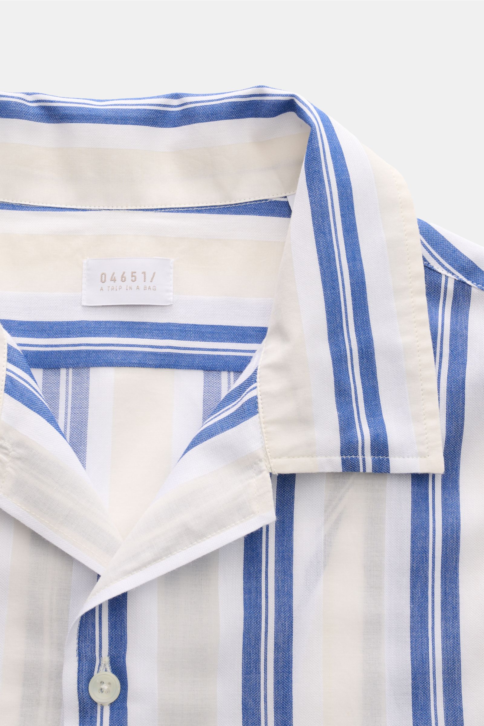 Close-up front view of 04651/ A trip in a bag Leinen-Kurzarmhemd Kubanischer Kragen pastellgelb, a pastel yellow linen short-sleeve shirt with blue and white stripes, Cuban collar, French placket, breathable fabric, and classic fit. 