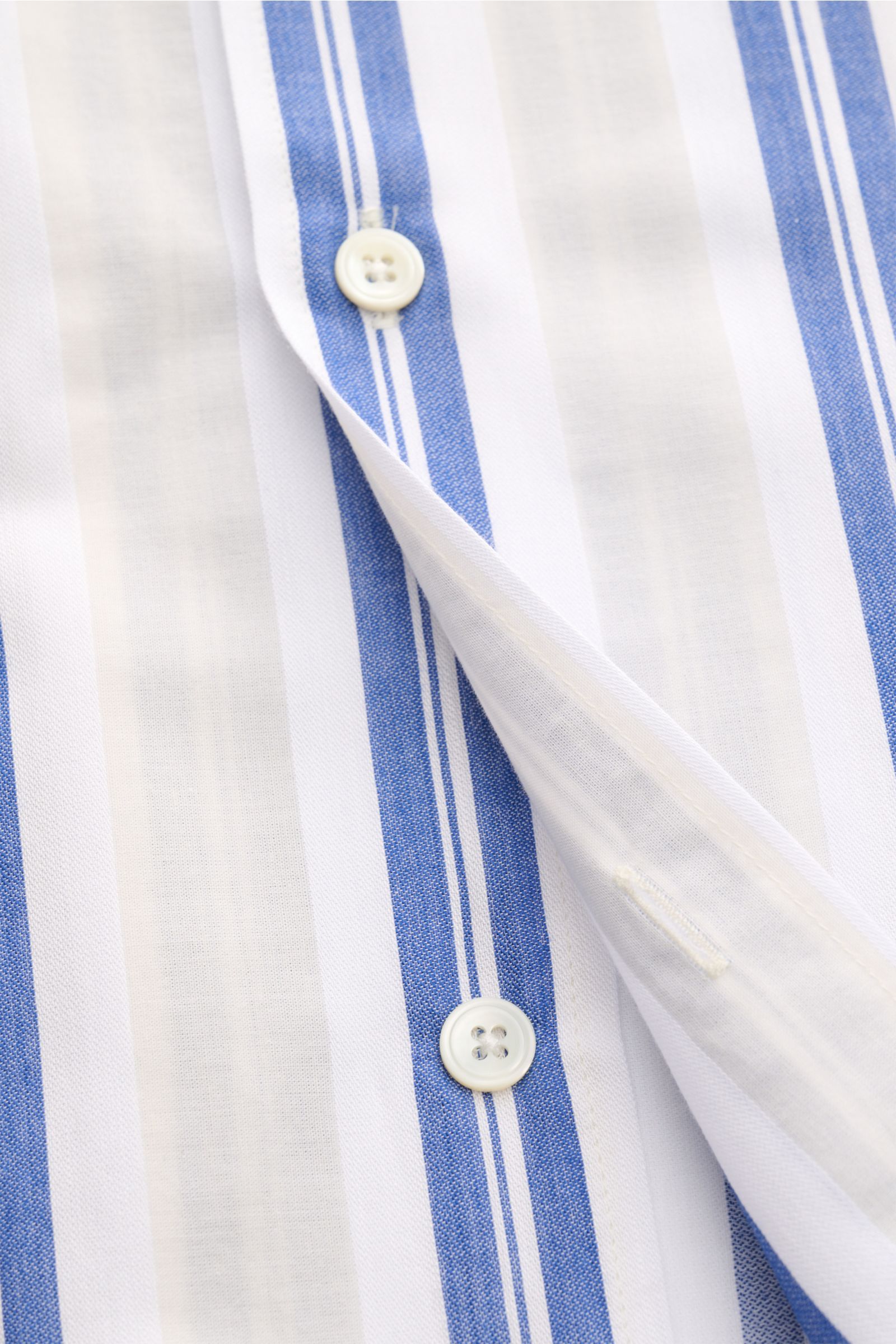Close-up front view of the 04651/ A trip in a bag Leinen-Kurzarmhemd Kubanischer Kragen pastellgelb showing white buttons on blue and white striped linen fabric. Mühelose Leichtigkeit
