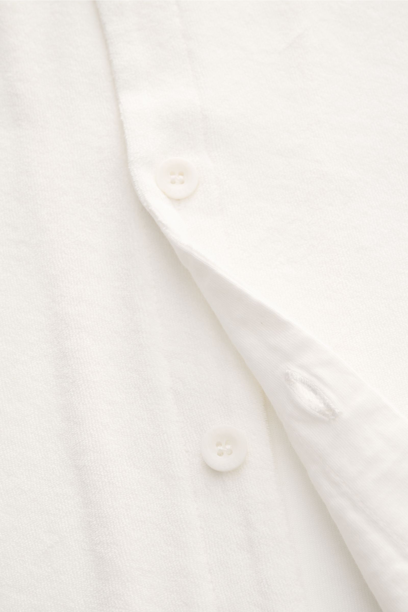 Close-up front view of 04651/ A trip in a bag Frottee-Kurzarmhemd 'Terry Cuba' offwhite, showing soft cotton terry fabric, button, and buttonhole; Urlaubsgefühl zum Anziehen: Das Kurzarmhemd 'Terry Cuba' von 04651/ A TRIP IN A BAG aus angenehmem Baumwoll-