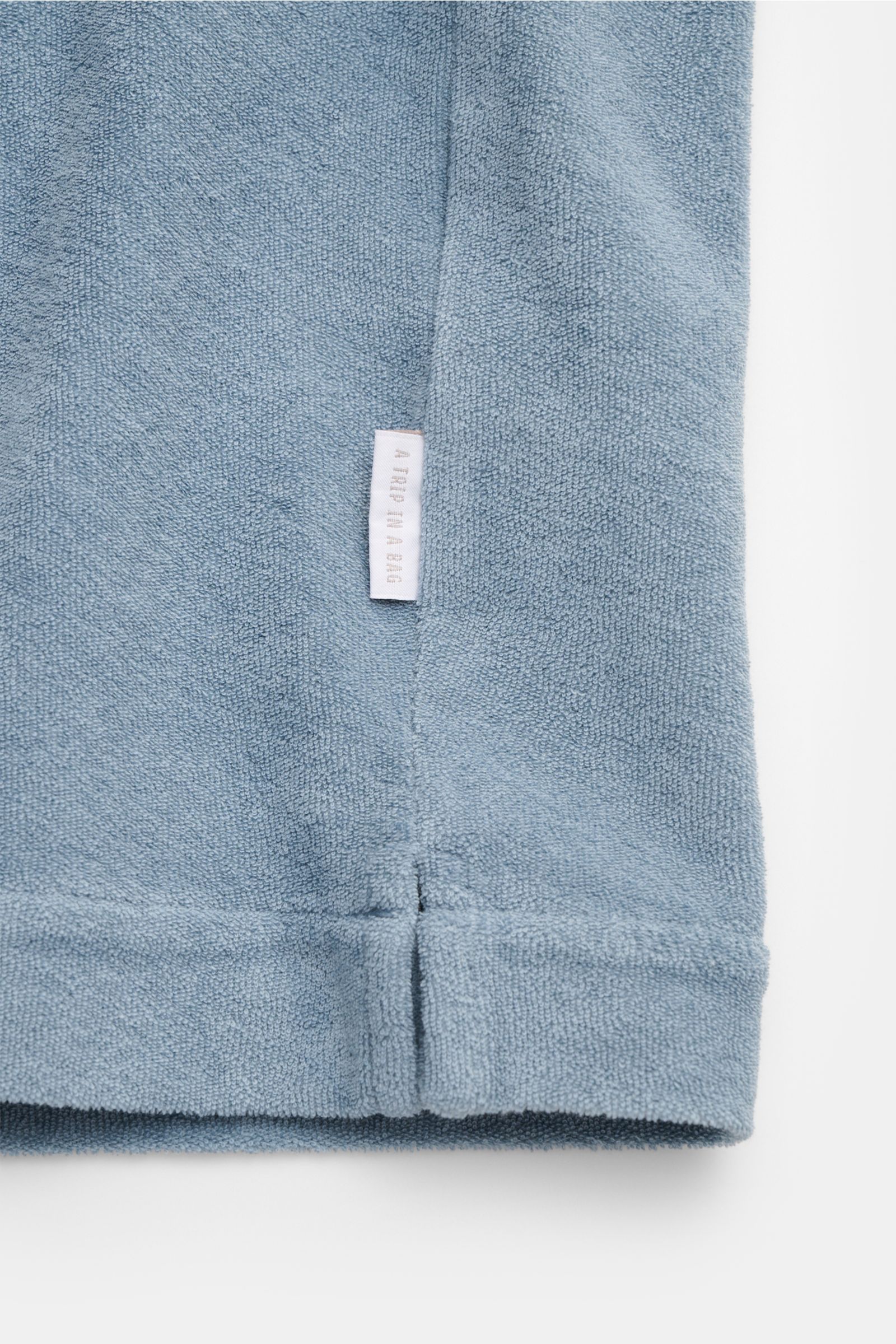 04651/ A trip in a bag Frottee-Kurzarmhemd 'Terry Cuba' rauchblau, Detailansicht Saum mit kurzem Schlitz und kleinem Weblabel, weicher Baumwoll-Frottee.