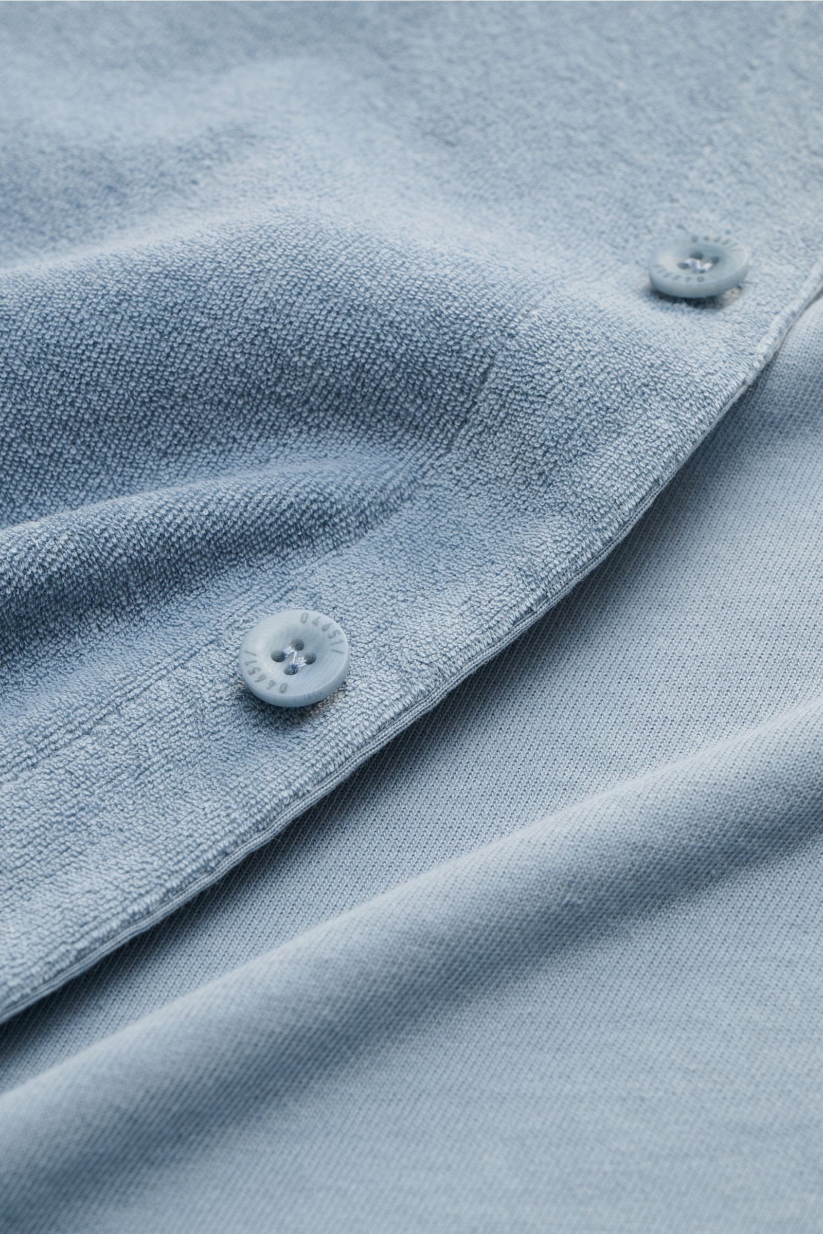 Nahaufnahme des 04651/ A trip in a bag Frottee-Kurzarmhemd 'Terry Cuba' rauchblau, Detail von Knöpfen und Baumwoll-Frottee-Struktur.