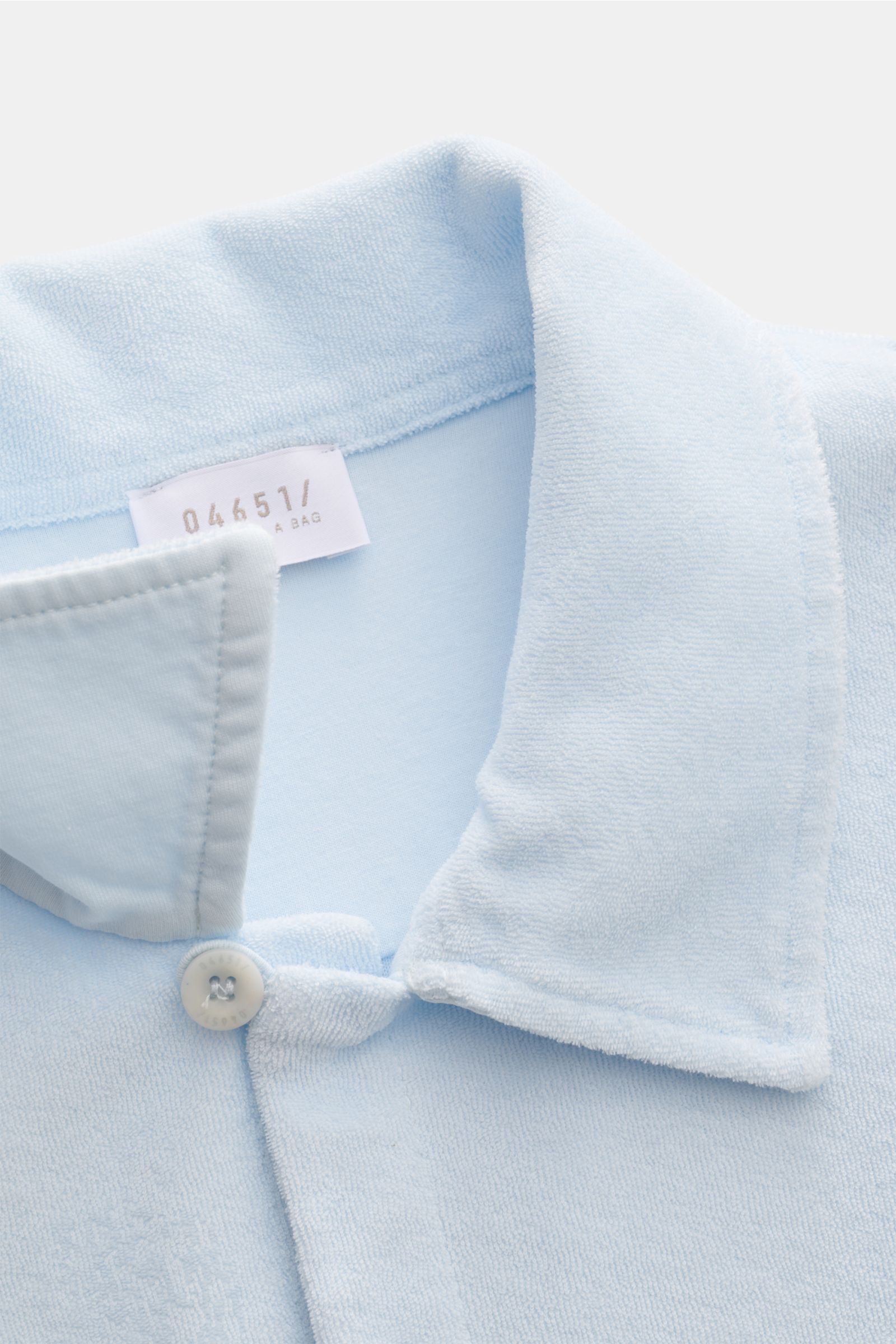 Close-up front perspective of the pastel blue 04651/ A trip in a bag Frottee-Kurzarmhemd 'Terry Cuba' with a soft cotton terry fabric, variable Cuban collar, French button placket, and small side seam label, embodying 'Urlaubsgefühl zum Anziehen' with sho