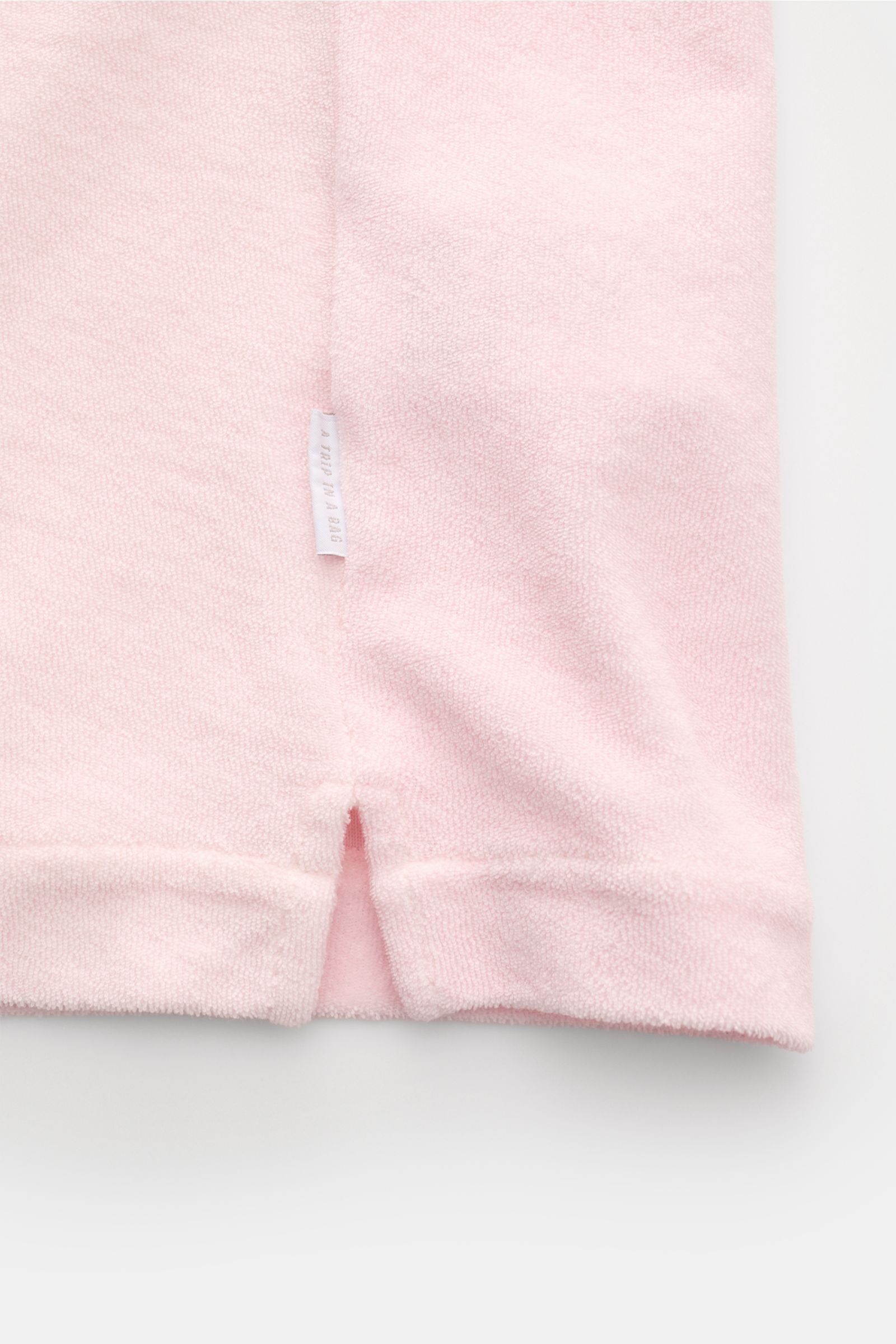 Close-up bottom view of the 04651/ A trip in a bag Frottee-Kurzarmhemd 'Terry Cuba' rosé showing soft pink cotton terry fabric with a small side seam label and short hem slit. Urlaubsgefühl zum Anziehen: Das Kurzarmhemd 'Terry Cuba' von 04651/ A TRIP IN A