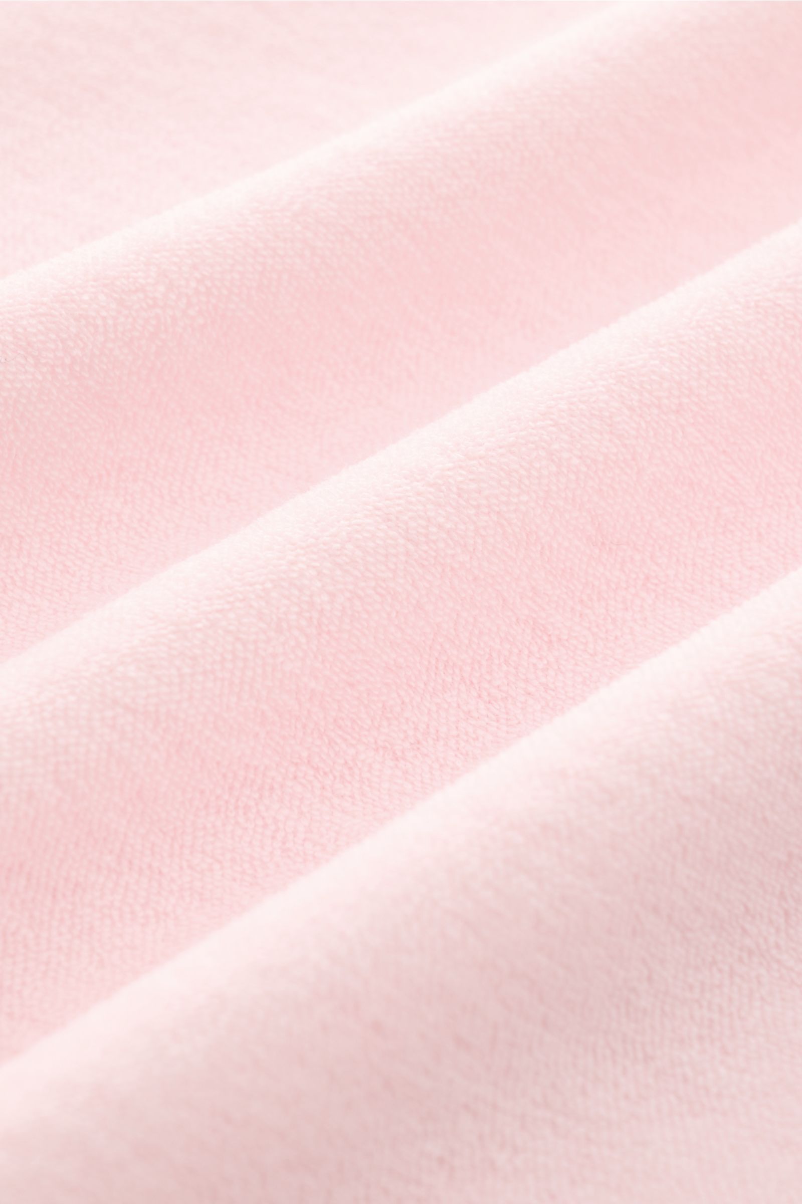 Das Bild zeigt eine Nahaufnahme der weichen Baumwoll-Frottee-Struktur in Rosé des 04651/ A trip in a bag Frottee-Kurzarmhemd 'Terry Cuba', fotografiert aus schräge oben. Urlaubsgefühl zum Anziehen: Das Kurzarmhemd 'Terry Cuba' von 04651/ A TRIP IN A BAG a