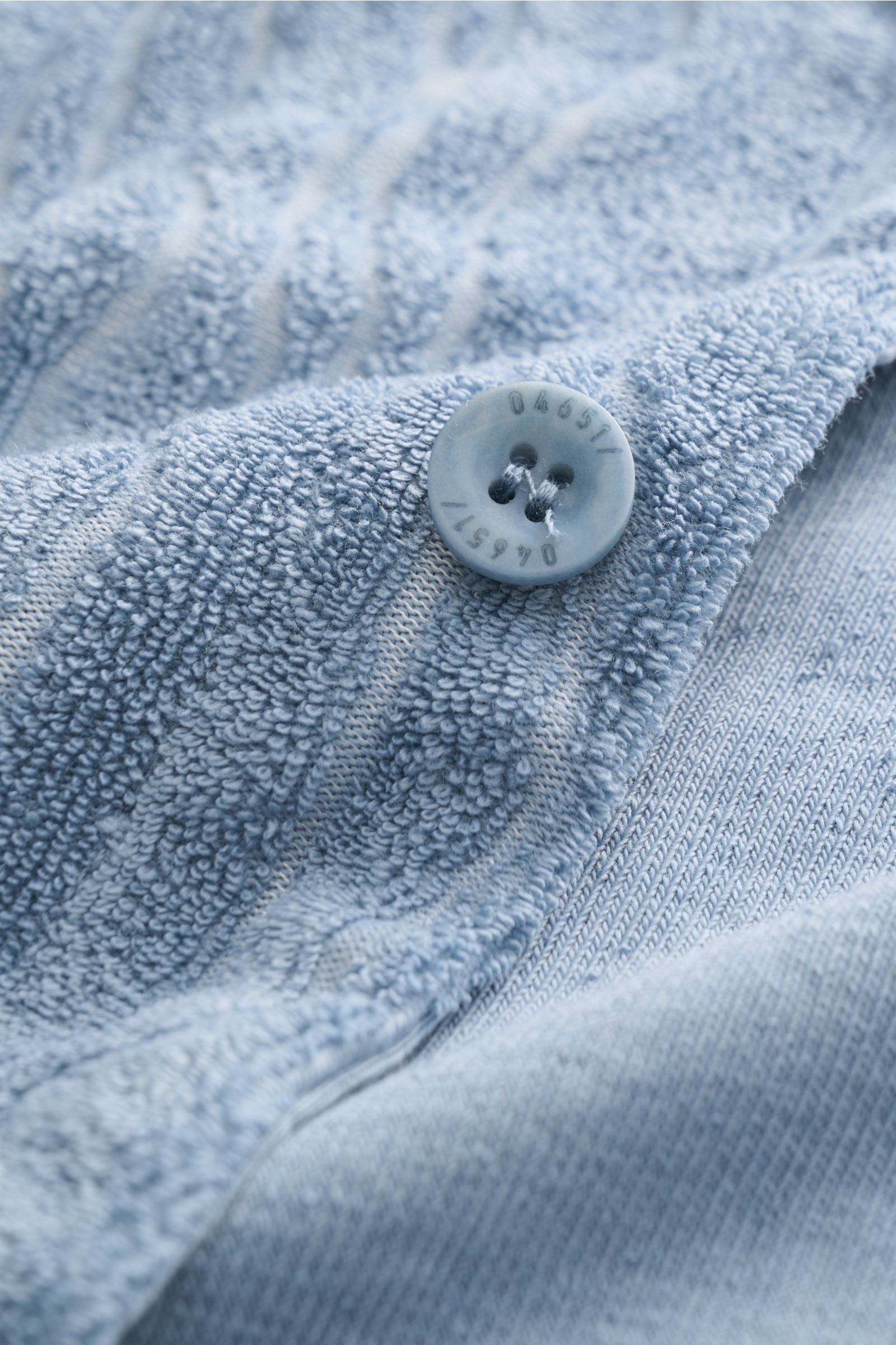 Nahaufnahme aus schräger Perspektive des rauchblauen 04651/ A trip in a bag Frottee-Kurzarmhemd 'Terry Superkilen' mit Knopf, weichem Griff, kubanischem Kragen und Allover-Muster.