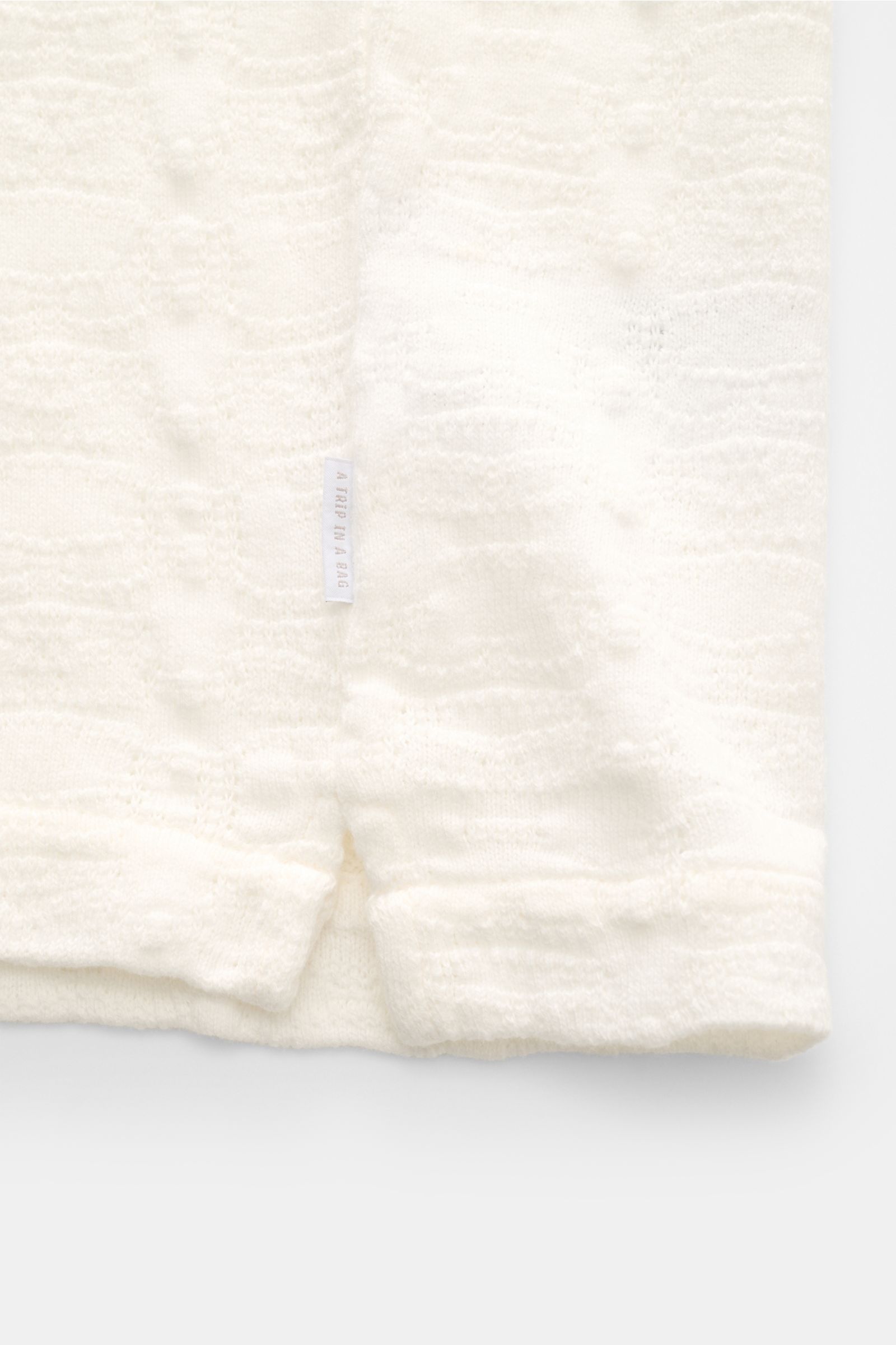 Cream-colored 04651/ A trip in a bag Jersey-Kurzarmhemd 'Abstract' Kubanischer Kragen creme shirt shown close-up from front, highlighting soft cotton, texture, and side logo label. Eyecatcher aus Jersey: Das Kurzarmhemd von 04651/ A TRIP IN A BAG wird mit