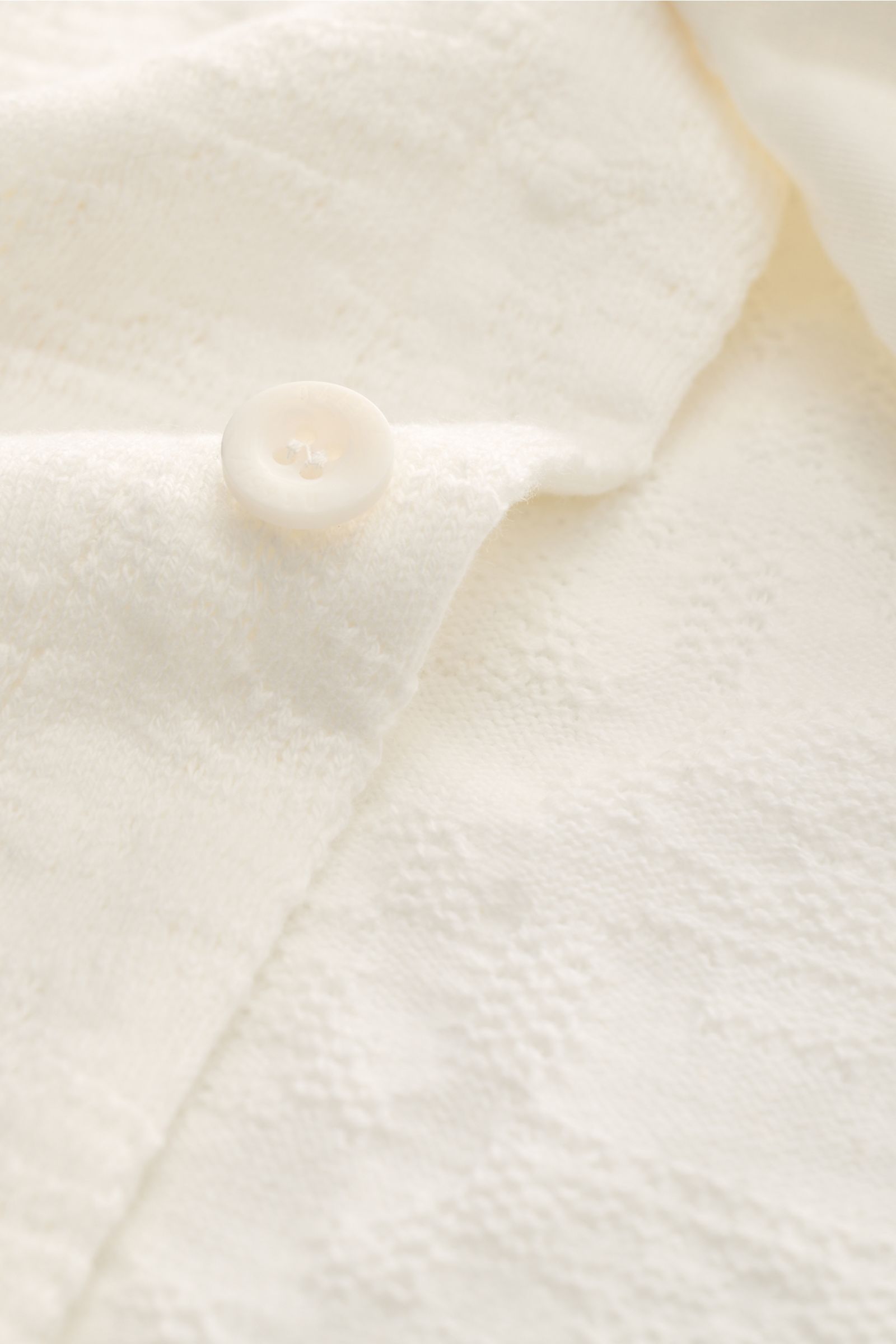 Close-up front view of the button and textured fabric of the 04651/ A trip in a bag Jersey-Kurzarmhemd 'Abstract' Kubanischer Kragen creme, a short-sleeve shirt made of pure cotton with a soft touch, regular fit, Cuban collar, French button placket, small