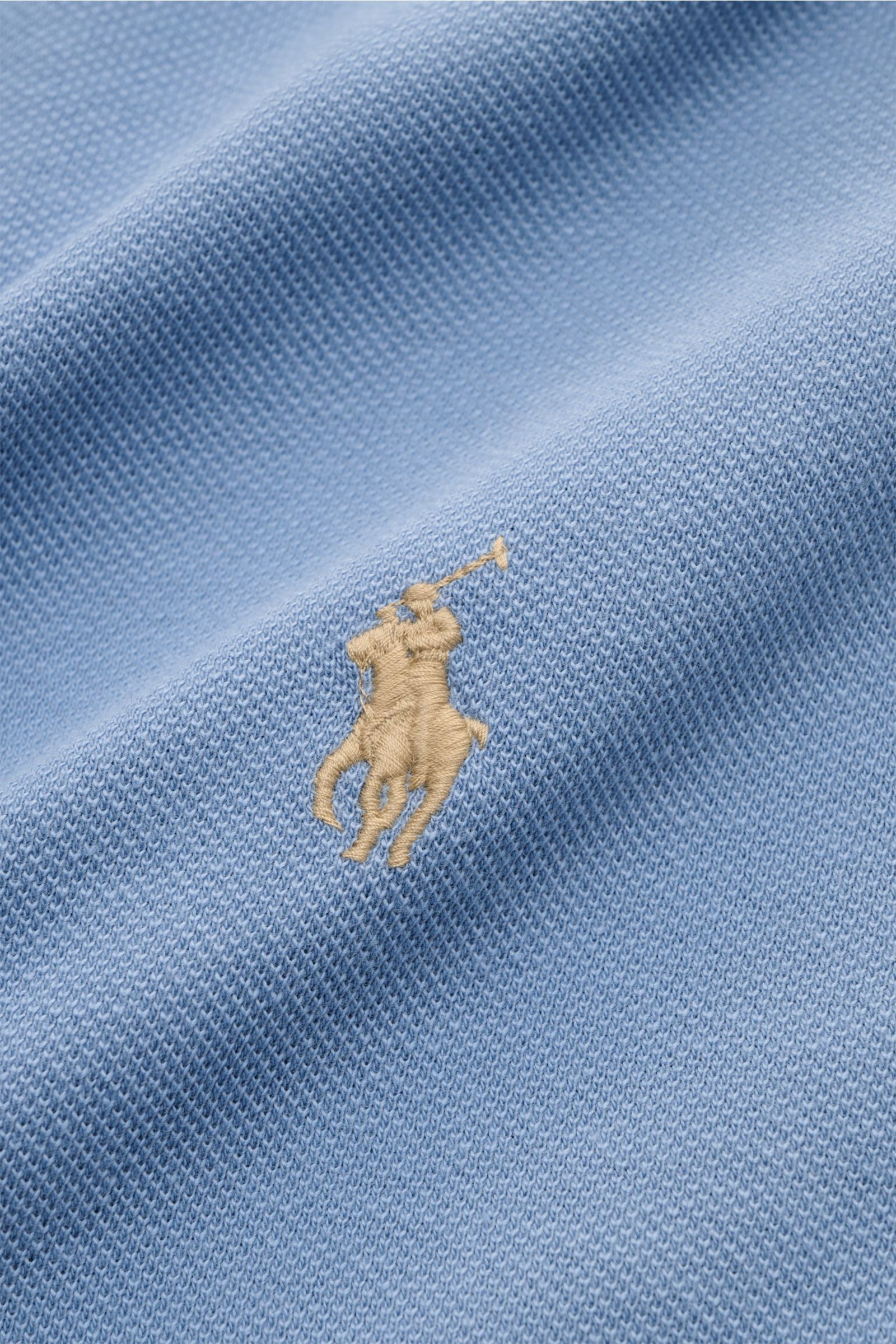 Close-up front view of the Polo Ralph Lauren Poloshirt hellblau showing the fine piqué texture and iconic beige polo player stitching on light blue cotton fabric. Seit 1972 der Klassiker unter den Poloshirts: Das ikonisches Piqué-Modell aus reiner Baum