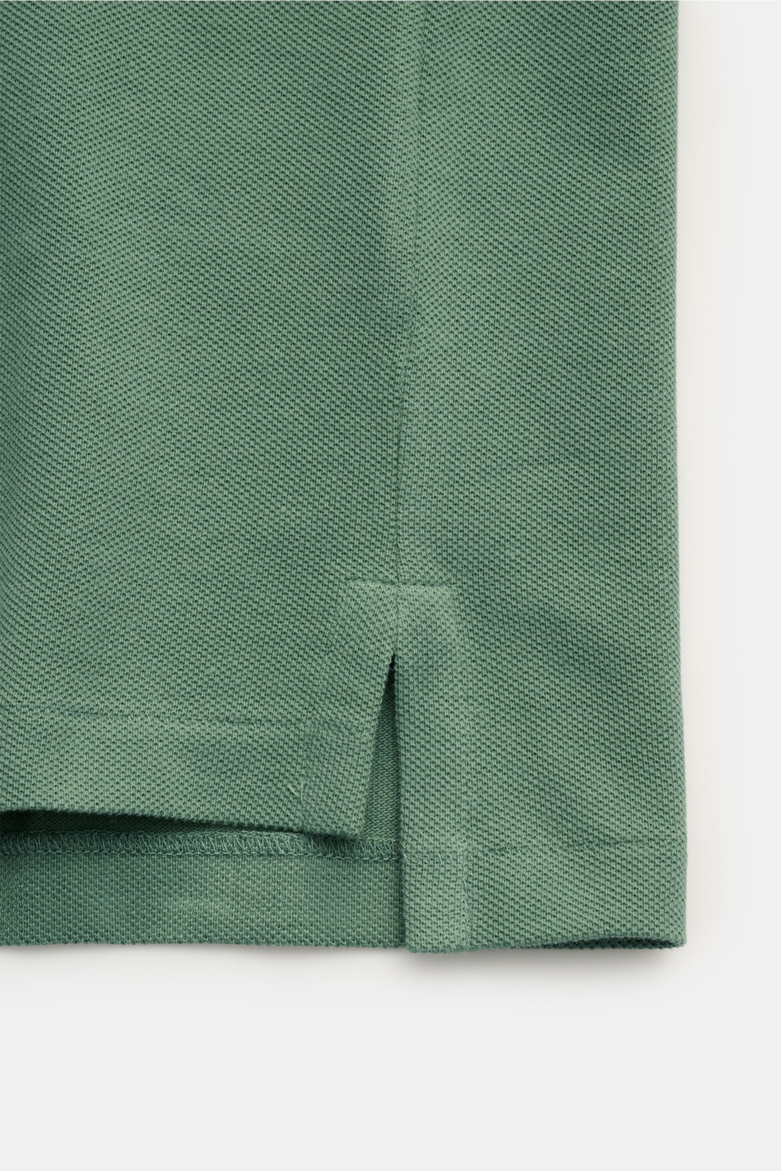 Nahaufnahme des Saumabschnitts eines Polo Ralph Lauren Poloshirts grün aus reiner Baumwolle mit feiner Piqué-Struktur und seitlichem Saumschlitz.