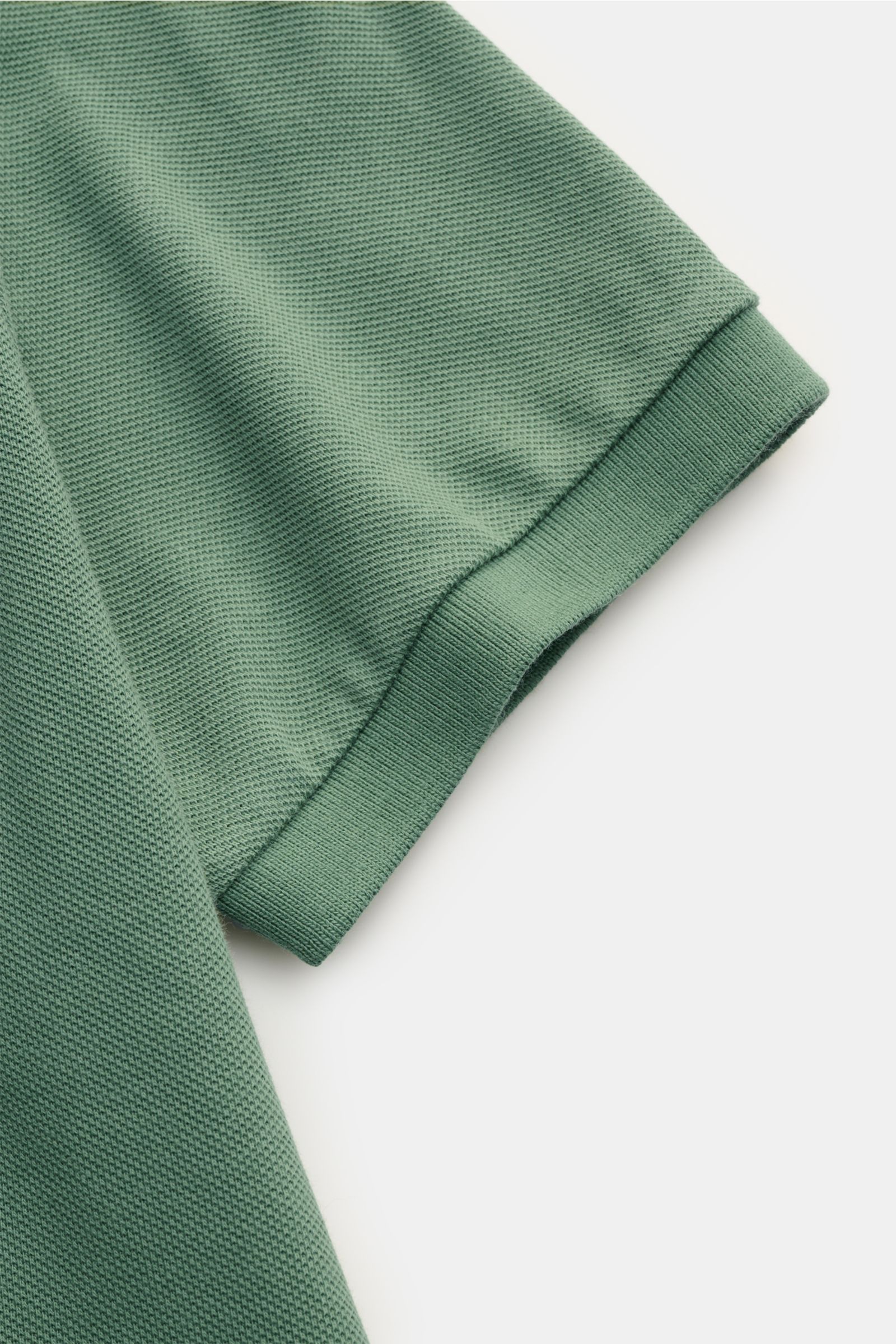 Nahaufnahme eines grünen Polo Ralph Lauren Poloshirts aus reiner Baumwolle, Piqué-Struktur, elastischem Ärmelbündchen, Slim Fit, fotografiert von oben schräg.