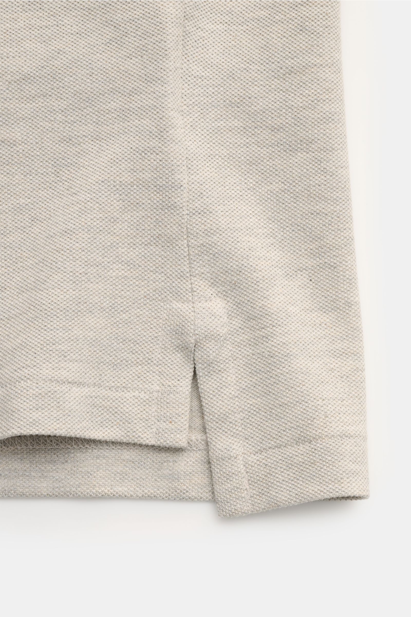 Polo Ralph Lauren Poloshirt hellgrau meliert, Detailansicht der seitlichen Saumschlitze und Piqué-Struktur aus reiner Baumwolle, Slim Fit, klassischer Polokragen, elastische Ärmelbündchen, ikonisches Poloreiter-Stitching seit 1972.