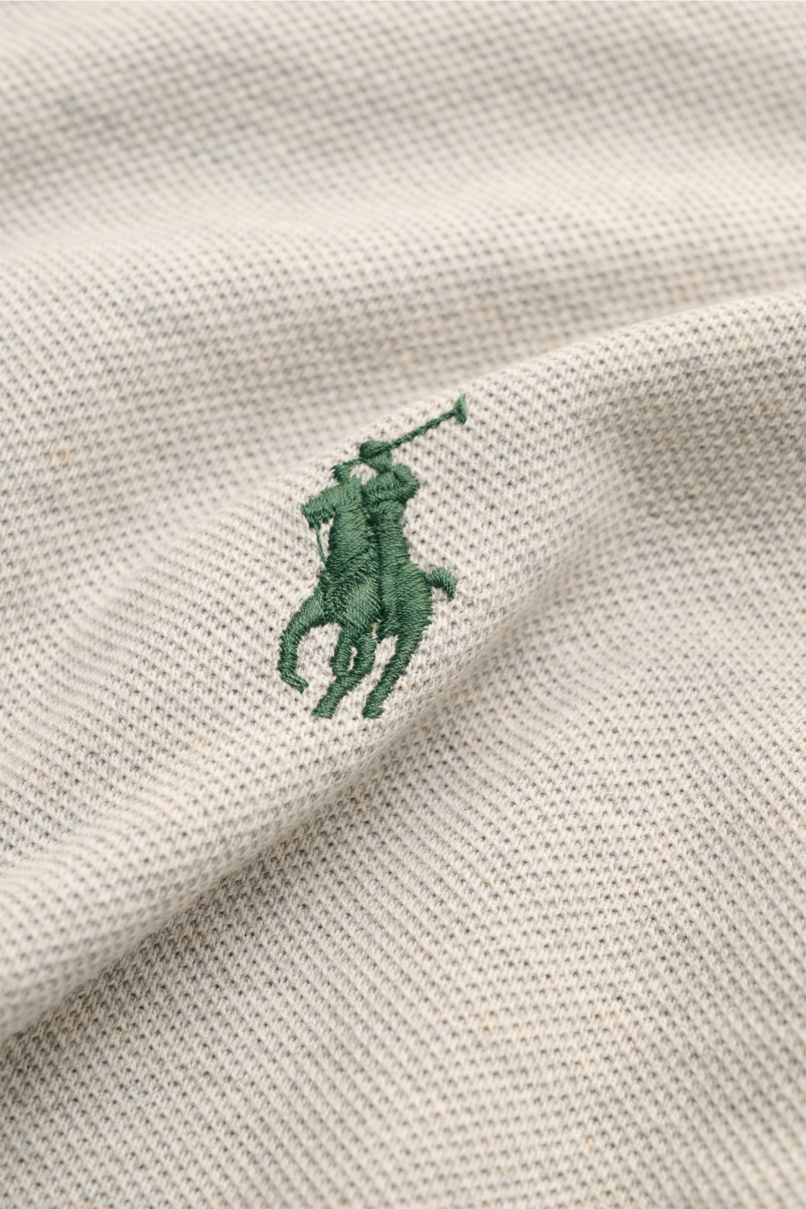 Nahaufnahme des ikonischen Polo Ralph Lauren Poloshirts hellgrau meliert mit grünem Poloreiter-Stitching auf feiner Piqué-Baumwollstruktur.