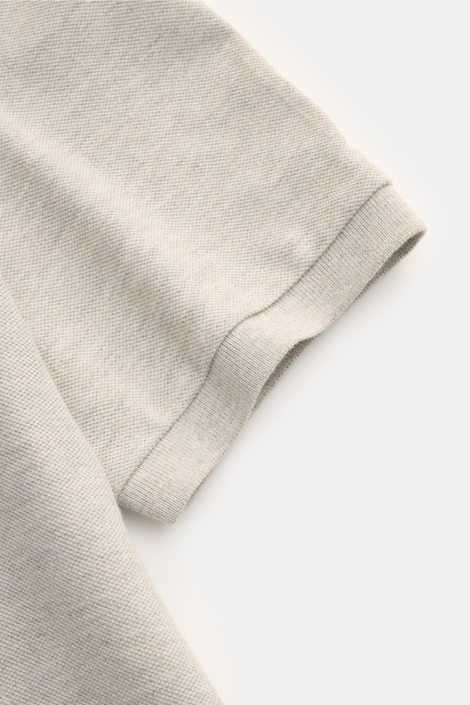Nahaufnahme eines hellgrau melierten Polo Ralph Lauren Poloshirts, Detail des Ärmels aus reiner Baumwolle mit feiner Piqué-Struktur.