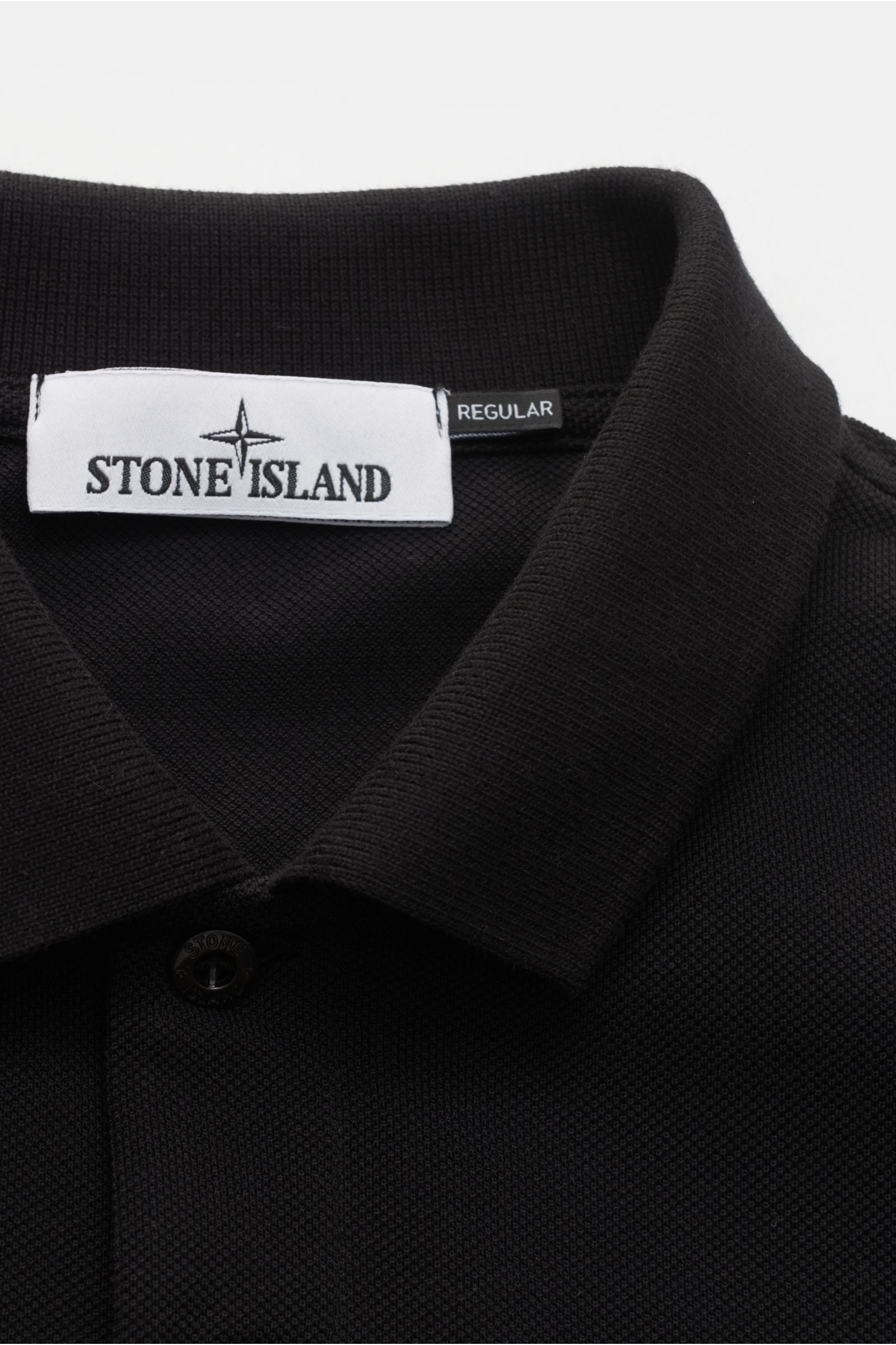 Close-up front view of Stone Island Poloshirt schwarz showing black cotton piqué fabric, typical polo collar, button placket, and Stone Island label.

Description: Das klassische Poloshirt ist ein Must-have in der sportiven Herrengarderobe: Aus Baumwol