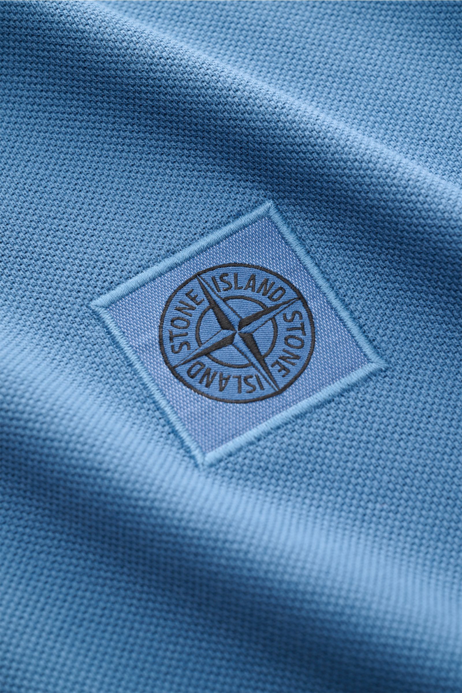 Stone Island Poloshirt graublau im Detail, Nahaufnahme des Baumwoll-Piqué mit STONE ISLAND-Weblabel, strukturierter Griff sichtbar.