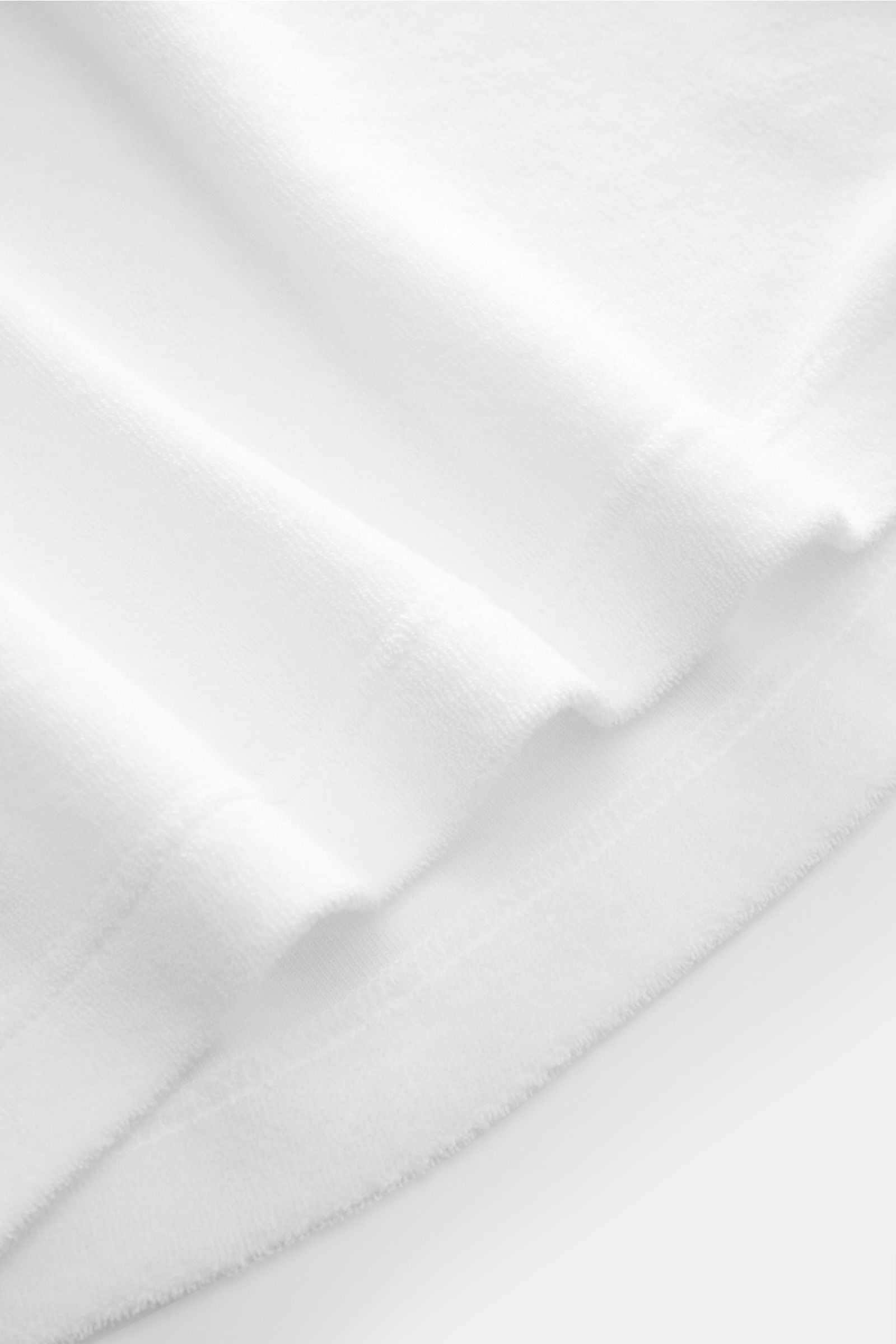 04651/ A trip in a bag Frottee-Poloshirt 'Terry Polo' weiß, Detailaufnahme der kurzen Saumschlitze aus weichem Baumwollfrottee, Regular Fit, Polokragen, Knopfleiste, kleines Weblabel.