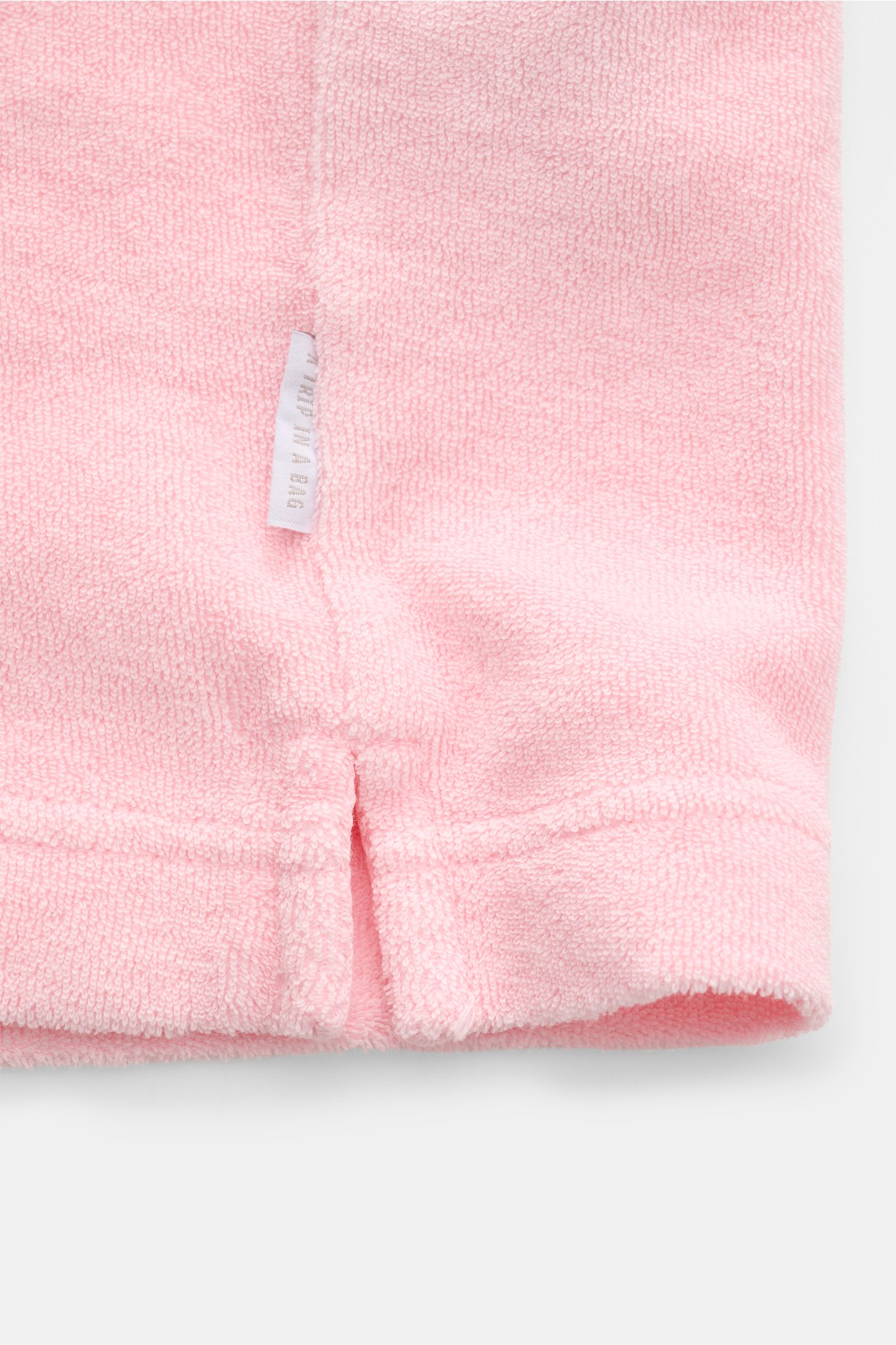 04651/ A trip in a bag Kinder Frottee-Poloshirt 'Kids Oyster Polo' rosé, Detailaufnahme Saum mit Weblabel aus Bio-Baumwolle.