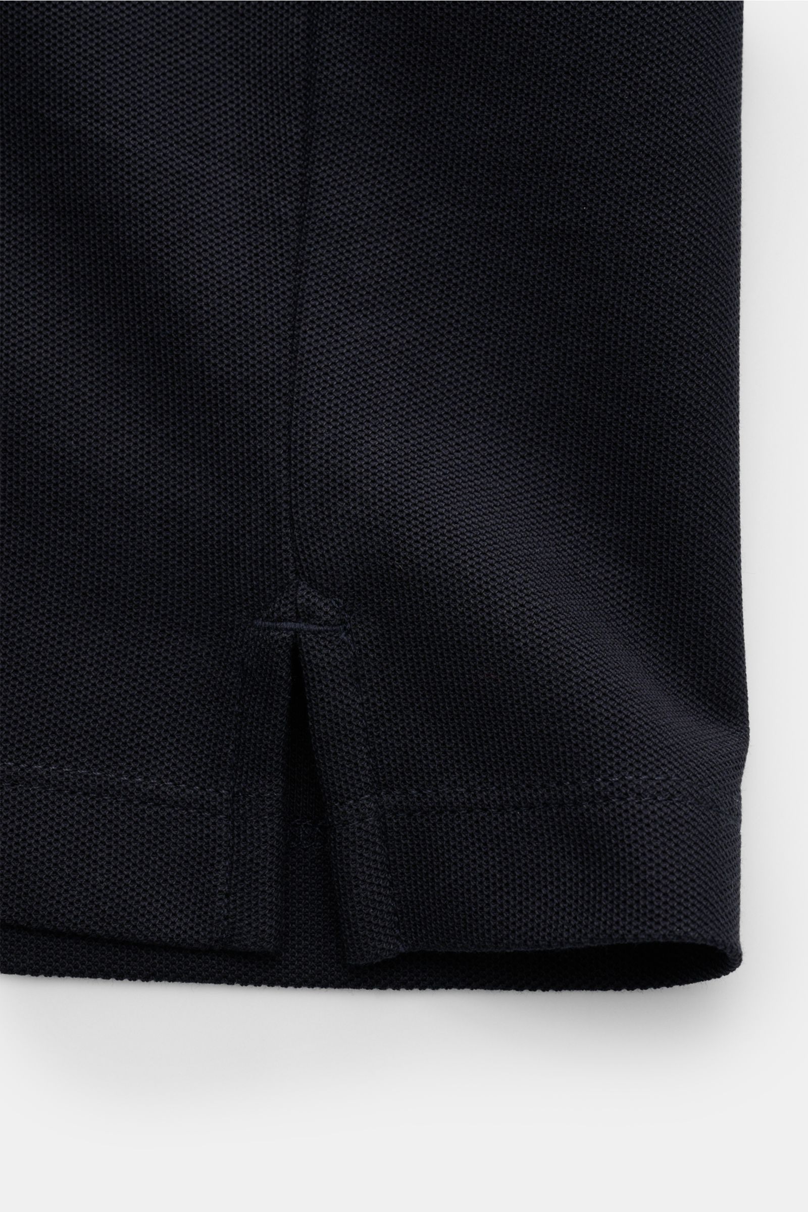 Close-up of the hem with side vents of the Emporio Armani Polo shirt navy, photographed from a front angle showing piqué cotton fabric texture. A versatile classic for sporty looks: This polo shirt by EMPORIO ARMANI has a timeless, casual design. Piqué je