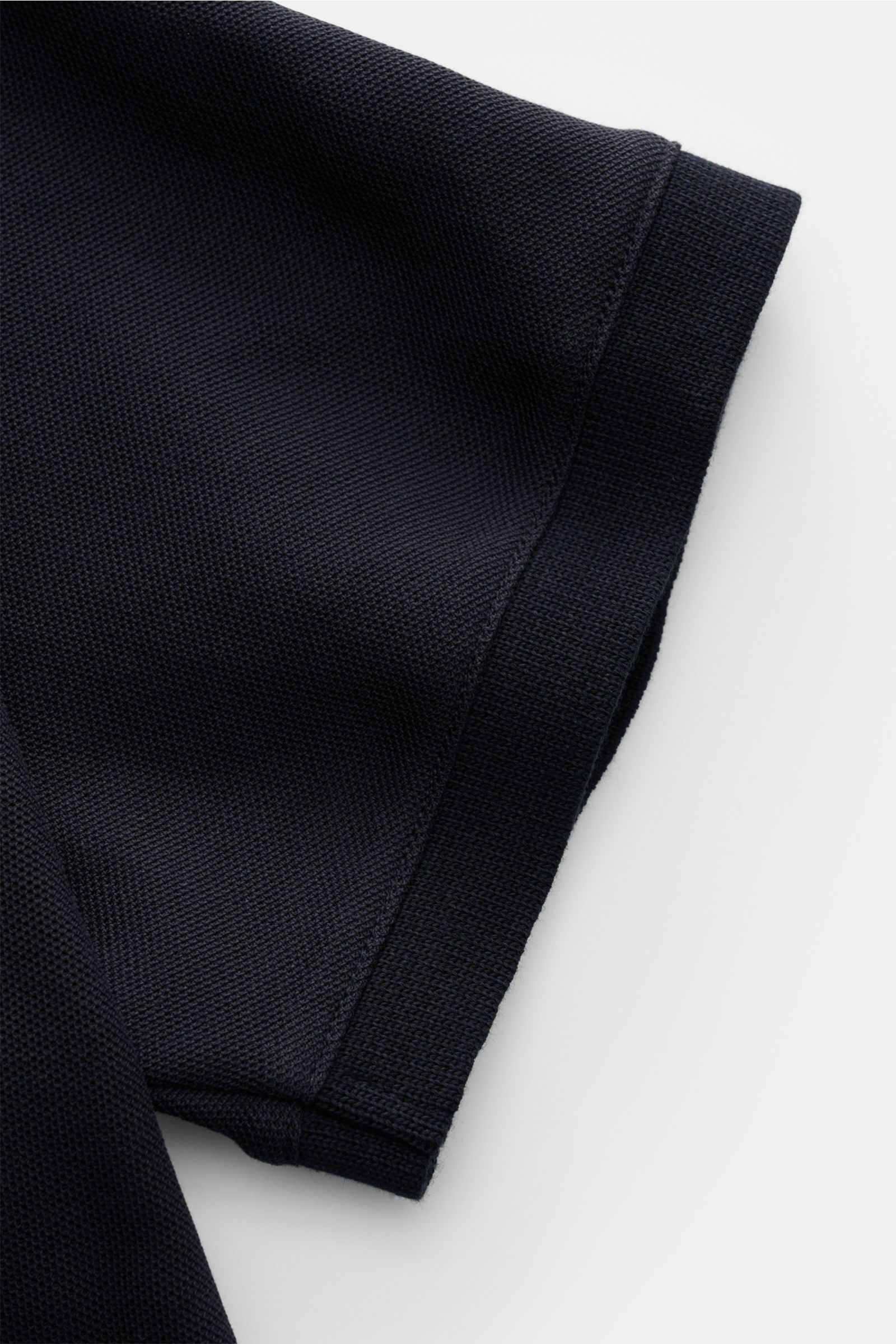 Close-up image of the sleeve of the Emporio Armani Polo shirt navy, photographed from above to highlight the piqué cotton fabric texture and hem with side vents. A versatile classic for sporty looks: This polo shirt by EMPORIO ARMANI has a timeless, casua