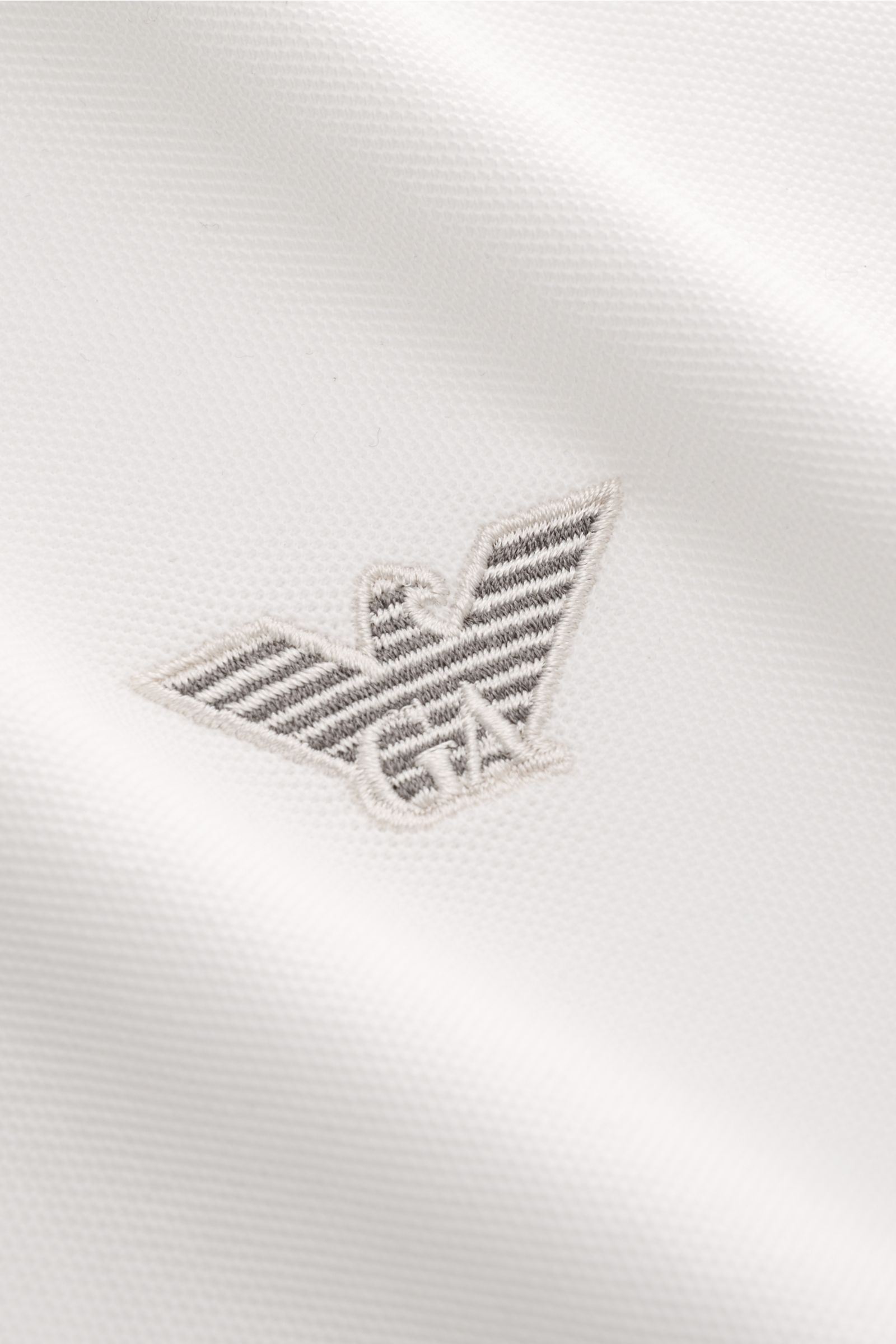 Close-up front view of the Emporio Armani Poloshirt offwhite showing the detailed label stitching on piqué-jersey cotton fabric with a lightly textured feel. Vielseitiger Klassiker für sportive Looks: Das Poloshirt von EMPORIO ARMANI überzeugt mit seinem 