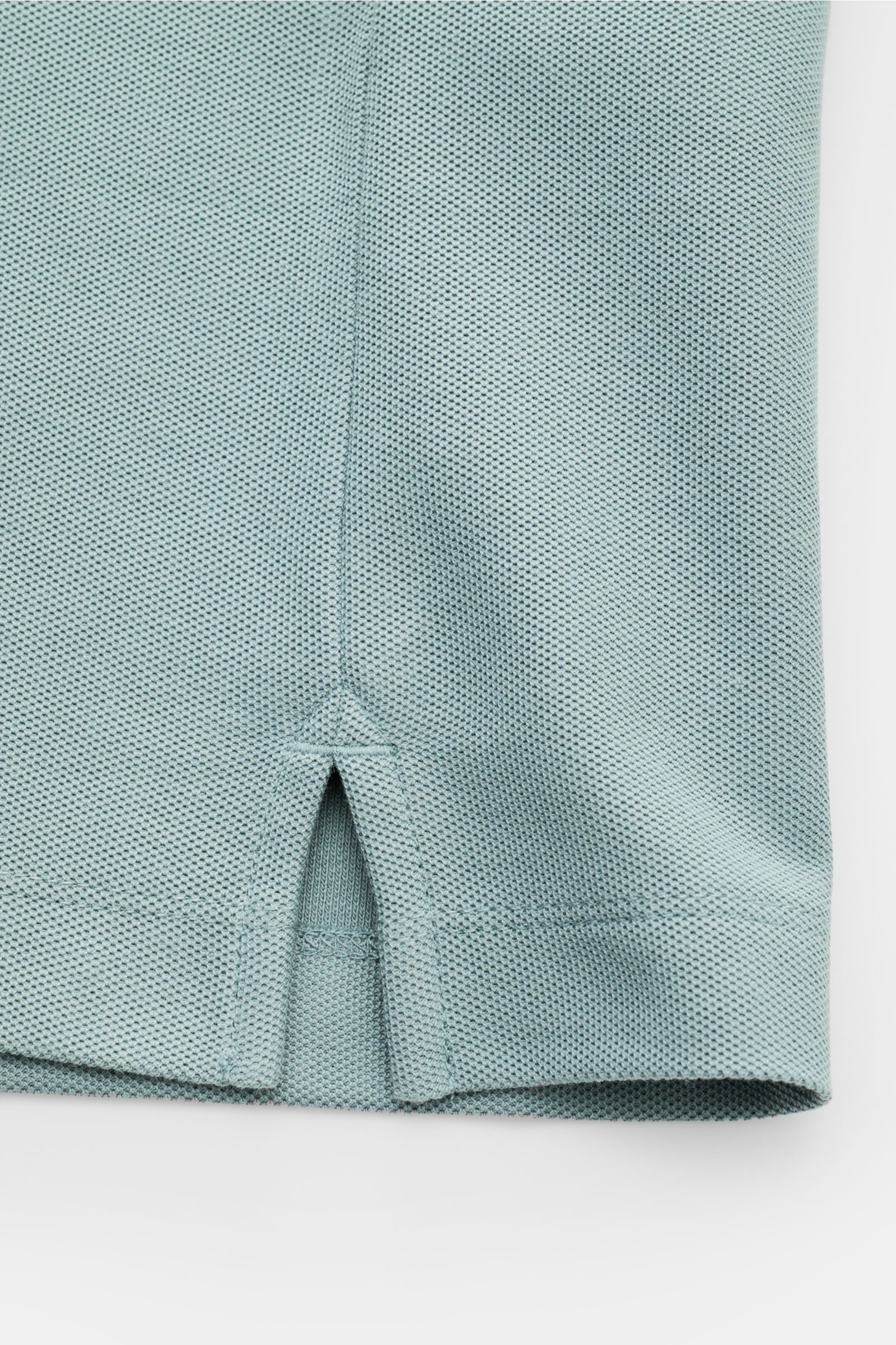 Close-up of the hem with side vents of the Emporio Armani Polo shirt sage, photographed from the side, showing piqué cotton fabric texture.

A versatile classic for sporty looks: This polo shirt by EMPORIO ARMANI has a timeless, casual design.
