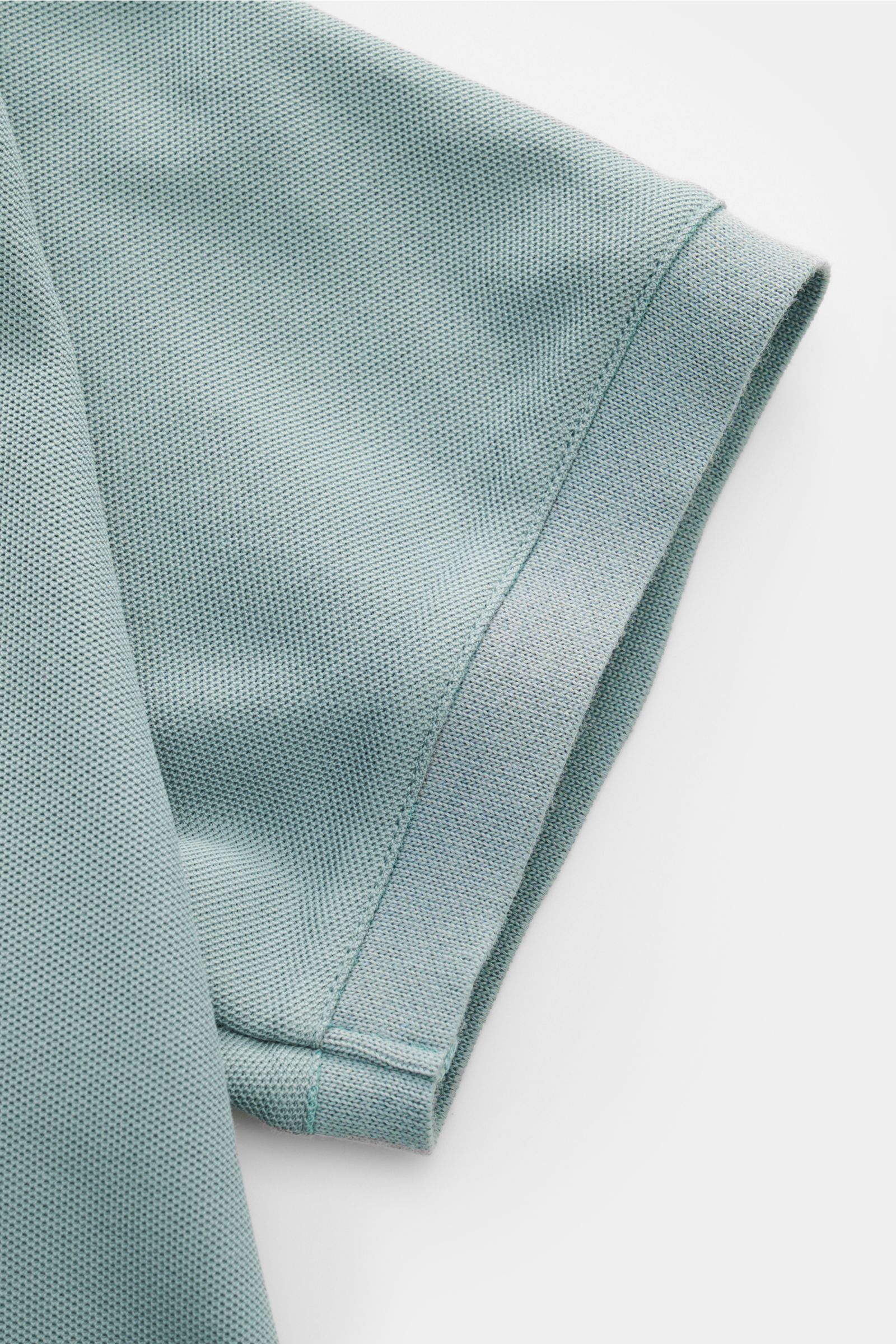Close-up side view of the sleeve of the Emporio Armani Polo shirt sage in piqué cotton jersey, showing label stitching and hem with side vents. A versatile classic for sporty looks: This polo shirt by EMPORIO ARMANI has a timeless, casual design.
