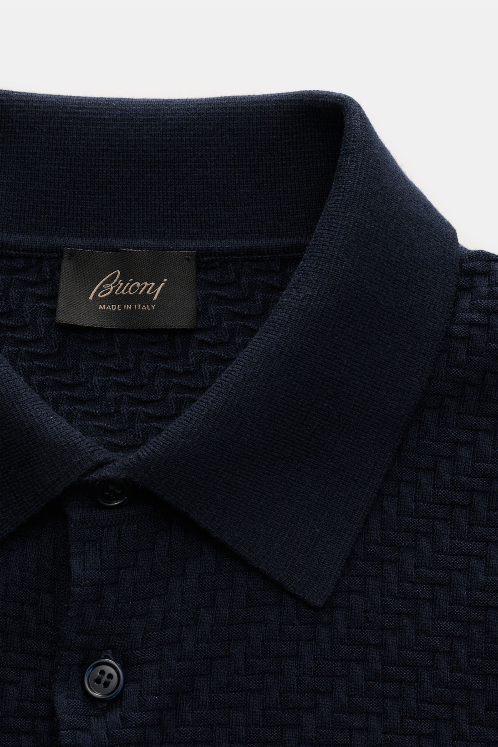 Nahaufnahme des Brioni Kurzarm-Strickpolo navy aus Baumwolle, Seide und Cashmere mit Intreccio-Flechtmuster, Polokragen und Perlmuttknöpfen.