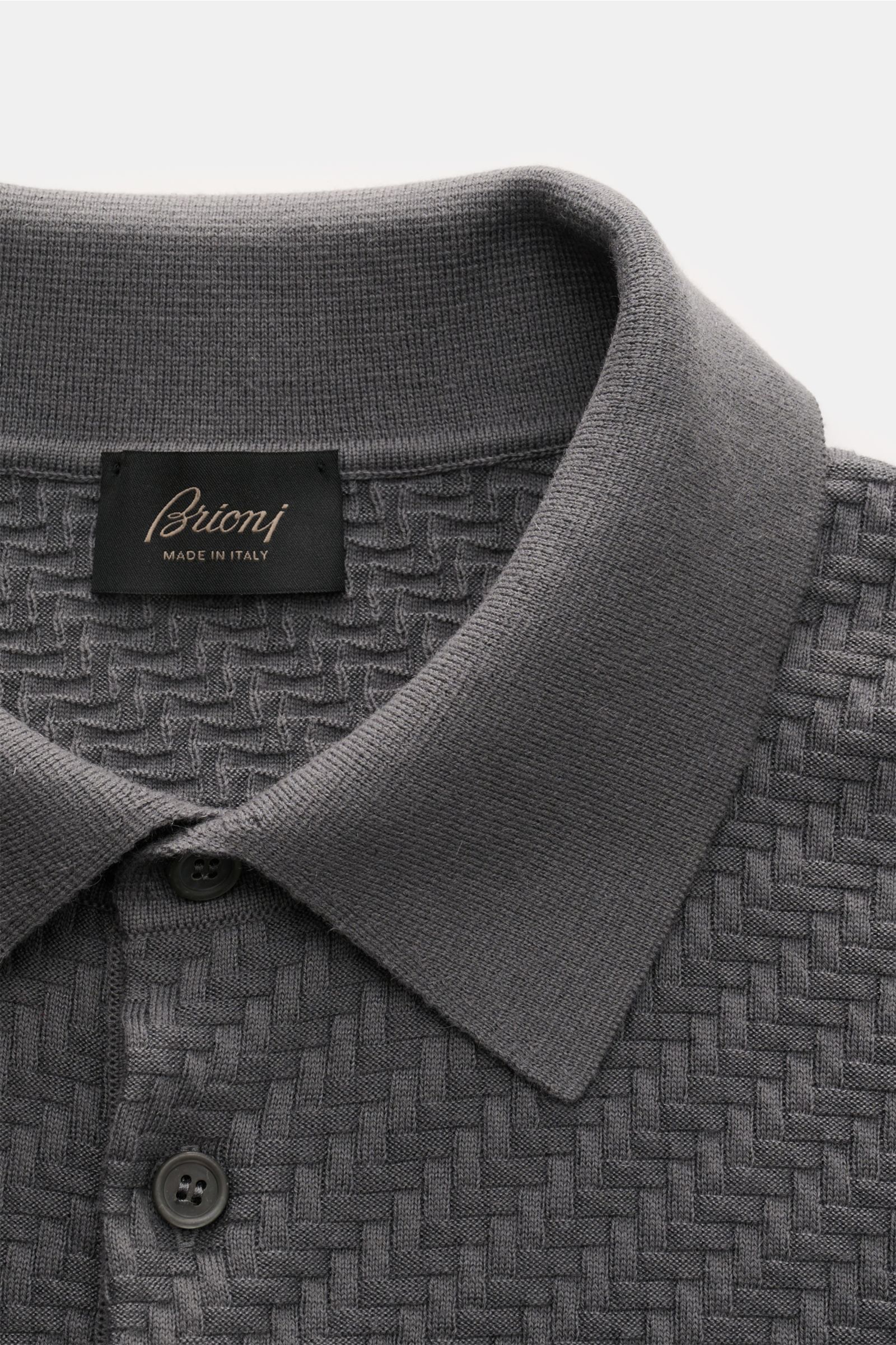 Brioni Kurzarm-Strickpolo dunkelgrau in Nahaufnahme von oben, mit Intreccio-Strickmuster, Polokragen und Perlmutt-Knöpfen.