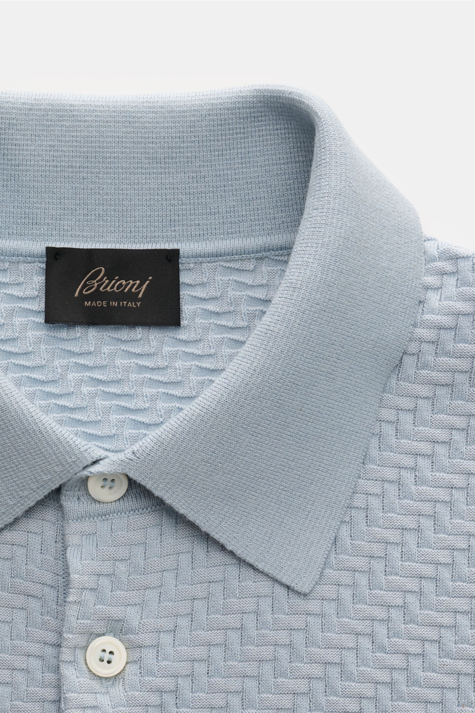 Brioni Kurzarm-Strickpolo hellblau in Nahaufnahme von oben, GOTS-Baumwolle, Seide, Cashmere, Intreccio-Muster, Polokragen, Perlmuttknöpfe.