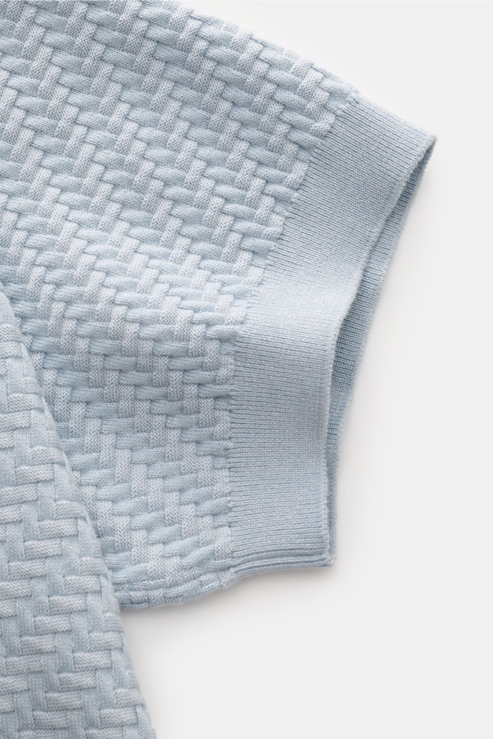 Brioni Kurzarm-Strickpolo hellblau in Nahaufnahme von oben, zeigt Intreccio-Flechtmuster, Rippbündchen, GOTS-Baumwolle, Seide, Cashmere.