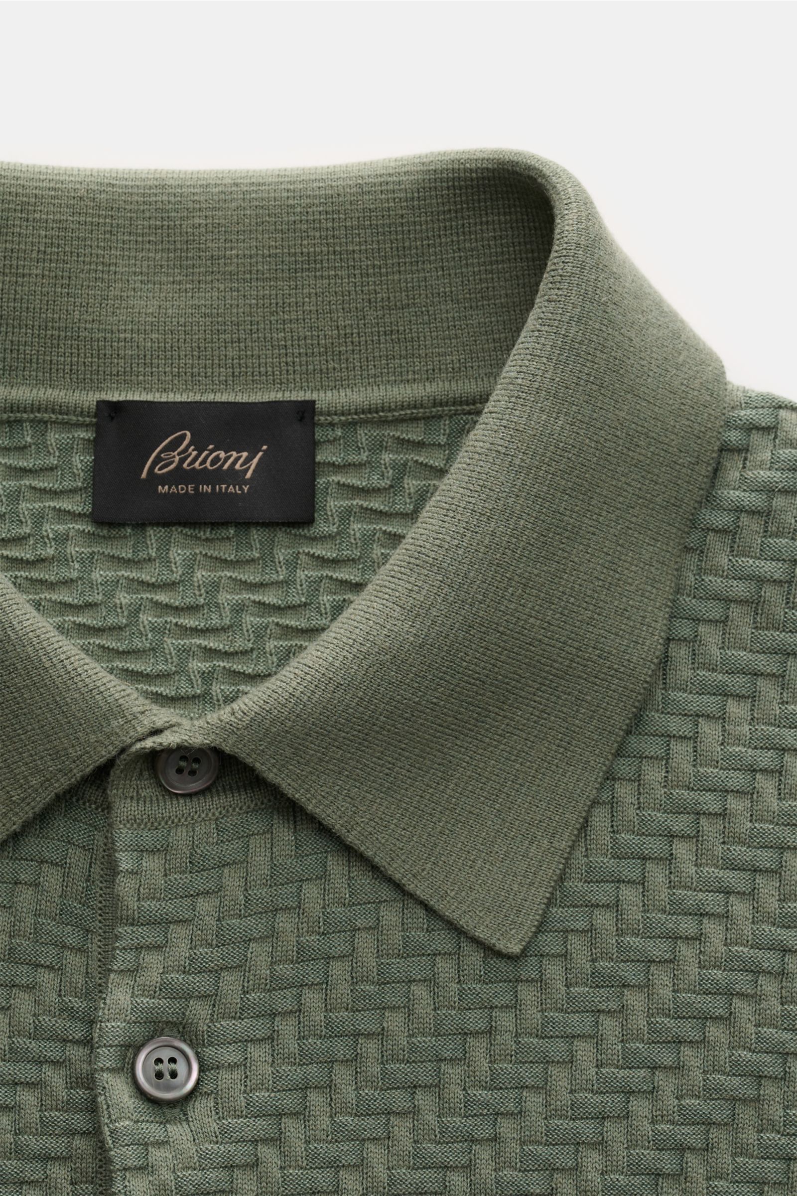 Brioni Kurzarm-Strickpolo graugrün in Nahaufnahme von oben, Struktur aus Baumwolle, Seide, Cashmere, Intreccio-Flechtmuster, Polokragen, Perlmuttknöpfe.