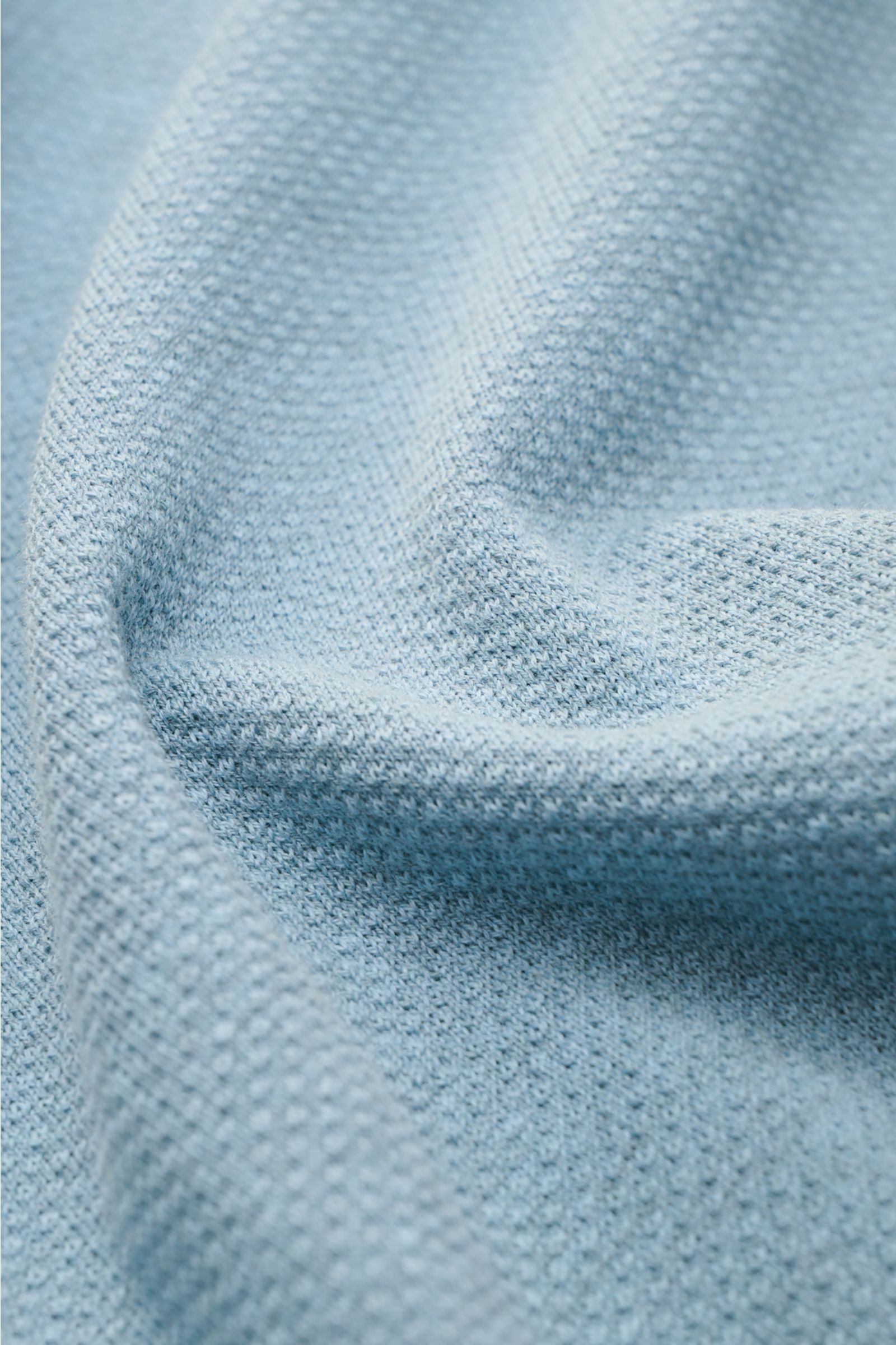 Close-up front view of the Brioni Kurzarm-Strickpolo rauchblau showing its airy knit texture made from pure cotton with a lightweight, slightly rough feel. Genießen Sie den Sommer stilvoll mit dem luftig gestrickten Polo von BRIONI - gefertigt aus reiner 