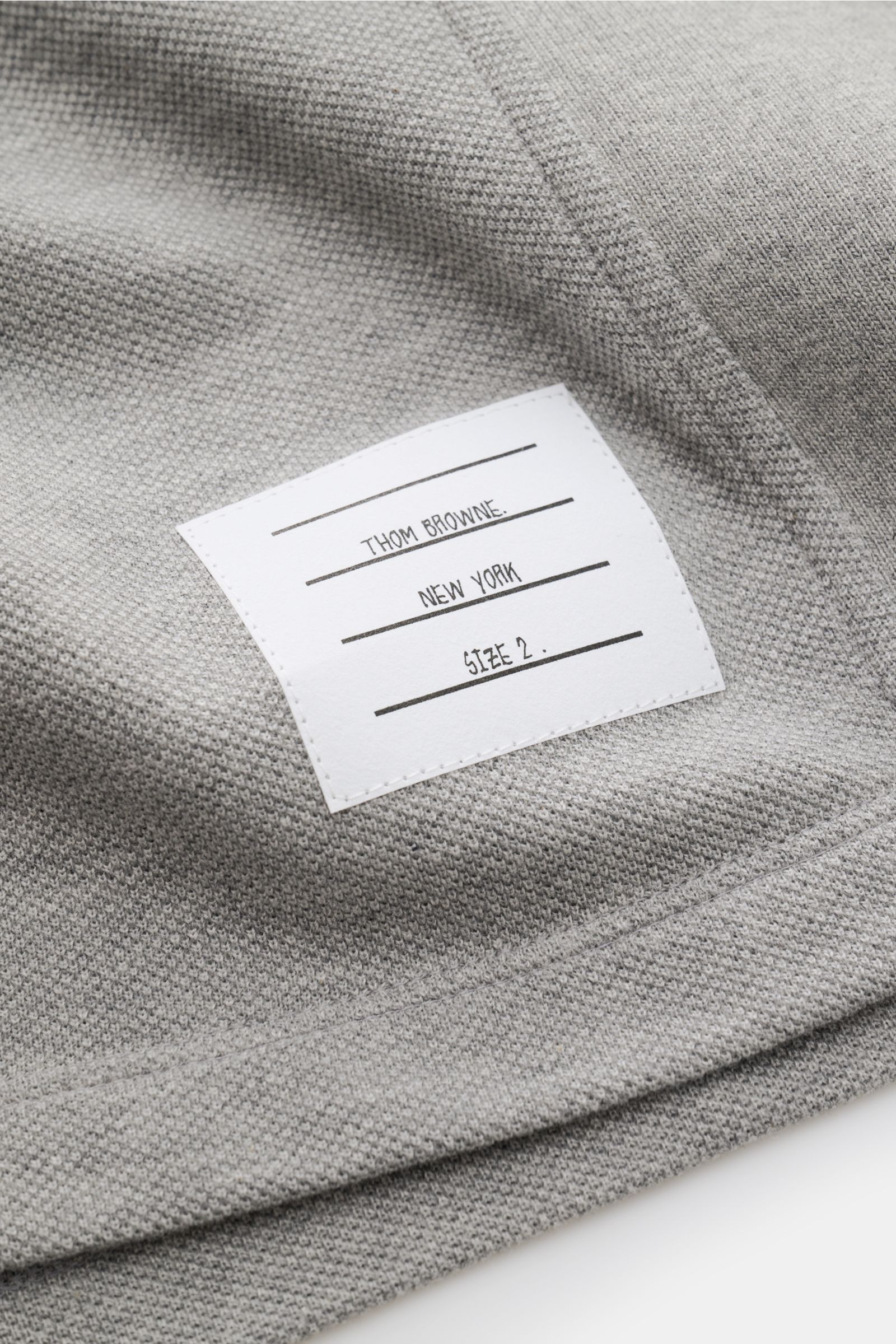 Close-up view of the Thom Browne Polo shirt grey mottled showing its textured pure cotton fabric and stitched brand label.

A modern essential: This polo shirt by THOM BROWNE is luxurious and comfortable, which makes it a sporty, elegant classic for yo