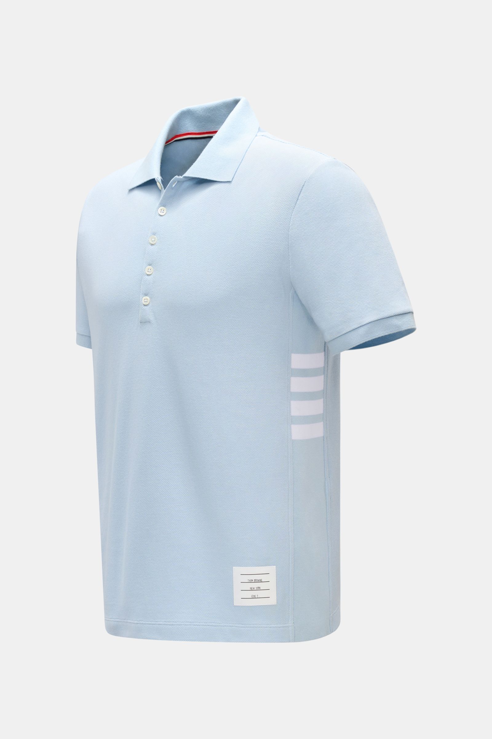 Thom Browne Poloshirt hellblau, Slim Fit, reine Baumwolle, fünf Knöpfe, Rippbündchen, Seiten mit elastischen Ripp-Einsätzen, seitliche Perspektive.