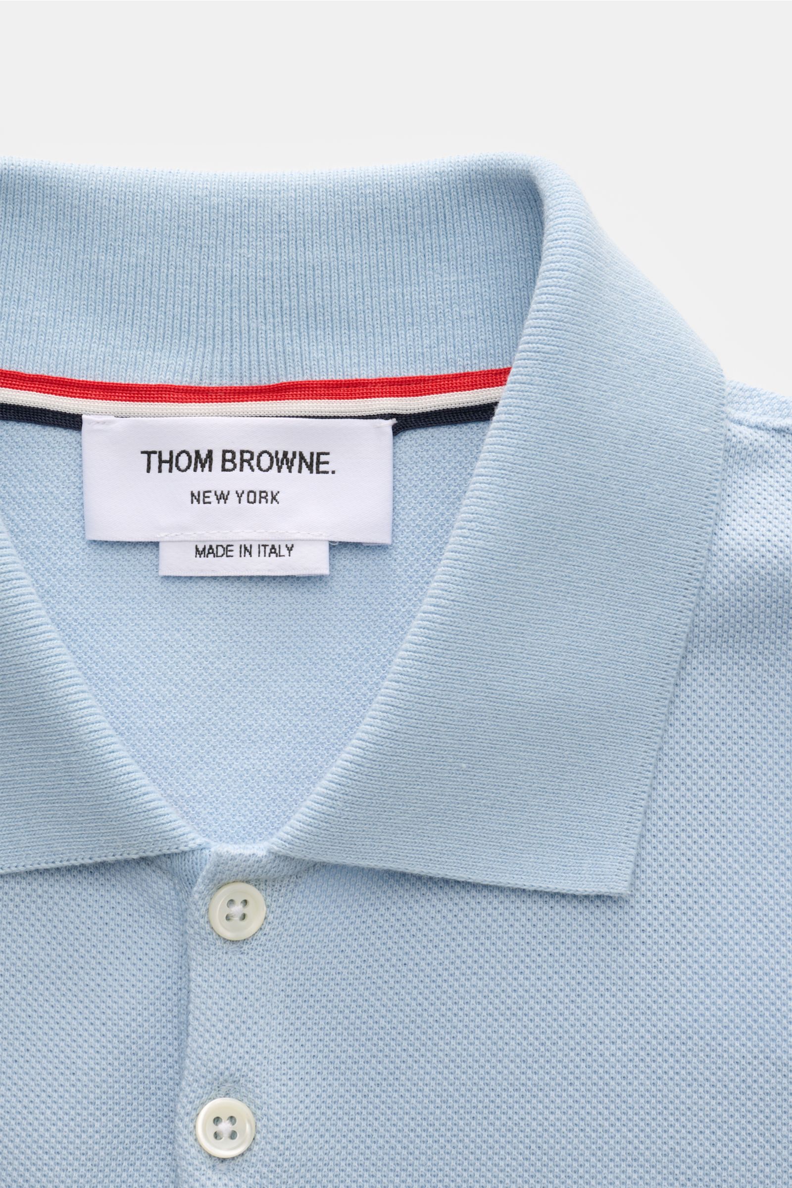 Thom Browne Poloshirt hellblau nah aus der Vogelperspektive, Slim Fit, reine Baumwolle, klassischer Polokragen, Fünf-Knopf-Leiste.