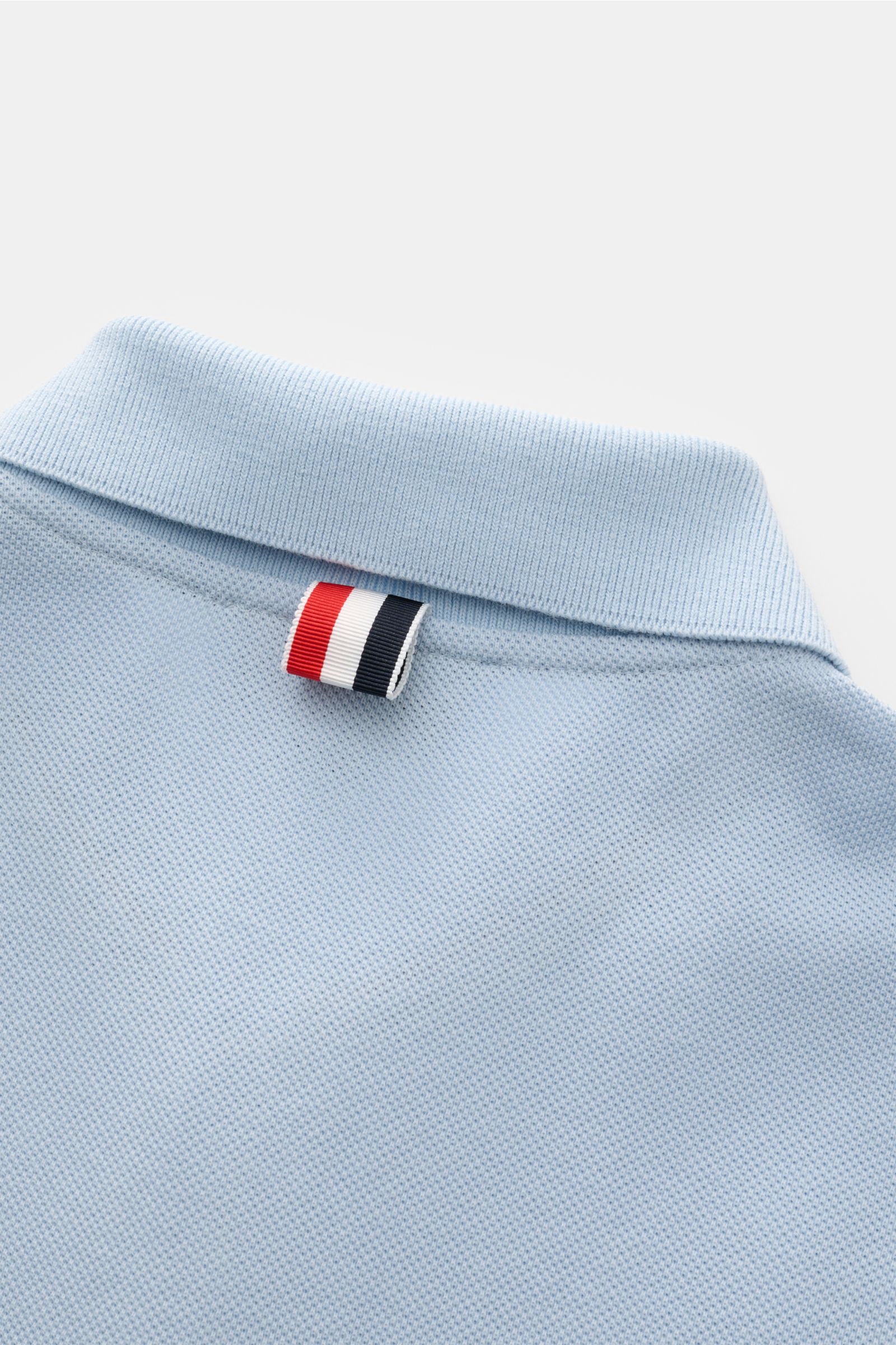 Thom Browne Poloshirt hellblau, Detailaufnahme von hinten oben, reine Baumwolle, strukturierte Slim Fit, klassischer Polokragen mit Streifen-Logo.