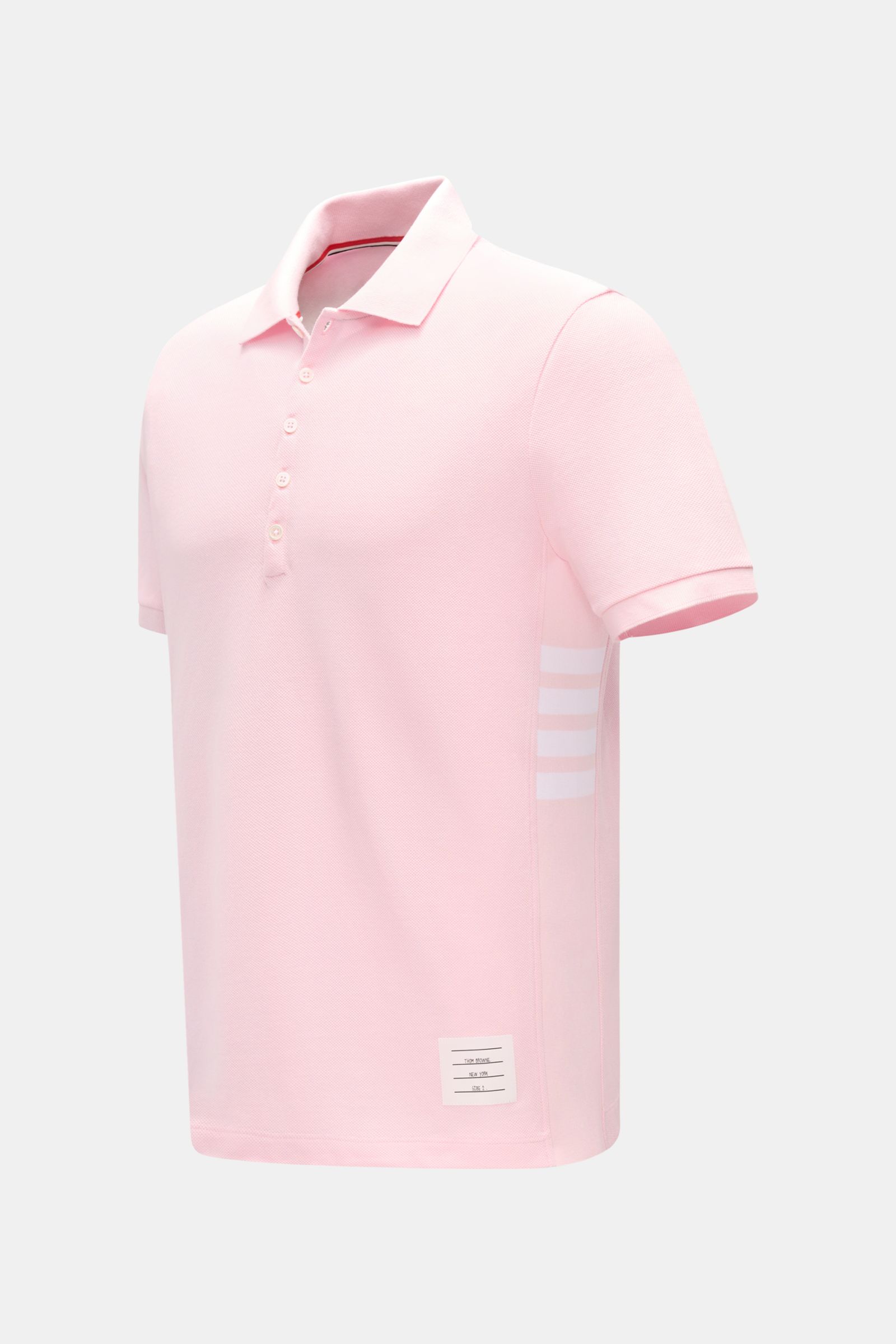 Front-right angled view of Thom Browne Poloshirt rosé in slim fit, made of pure cotton with a classic collar, five-button placket, ribbed sleeve cuffs, elastic side rib inserts, and signature stripe logo. Modern essential with luxurious comfort and sporty