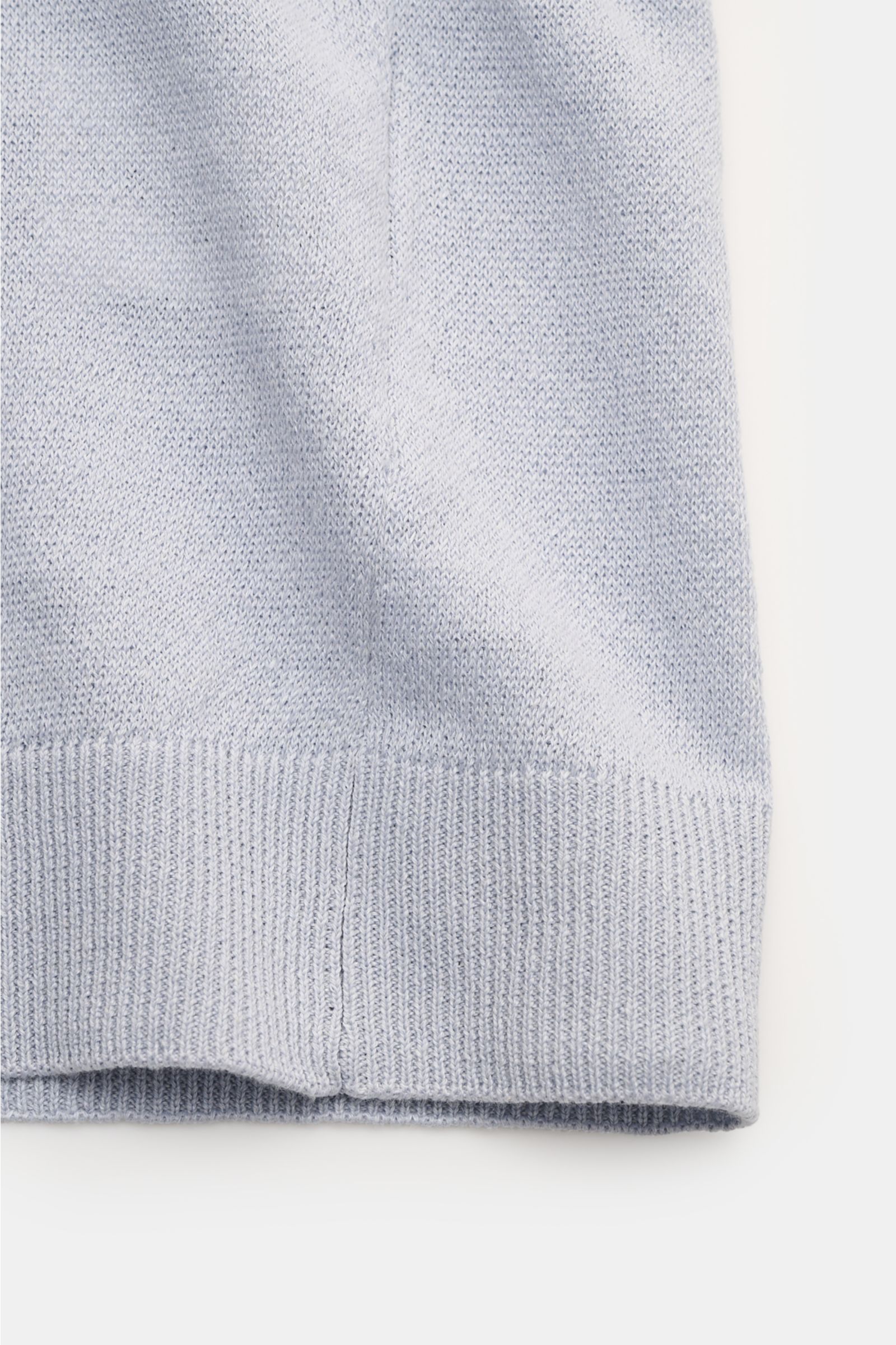 Close-up view of the lower hem of the Lardini Short sleeve knit polo smoky blue, showcasing its fine, airy linen and cotton blend knit with flexible ribbed bands. Elegance for the warmer seasons from LARDINI: This short-sleeved knit polo made from a linen