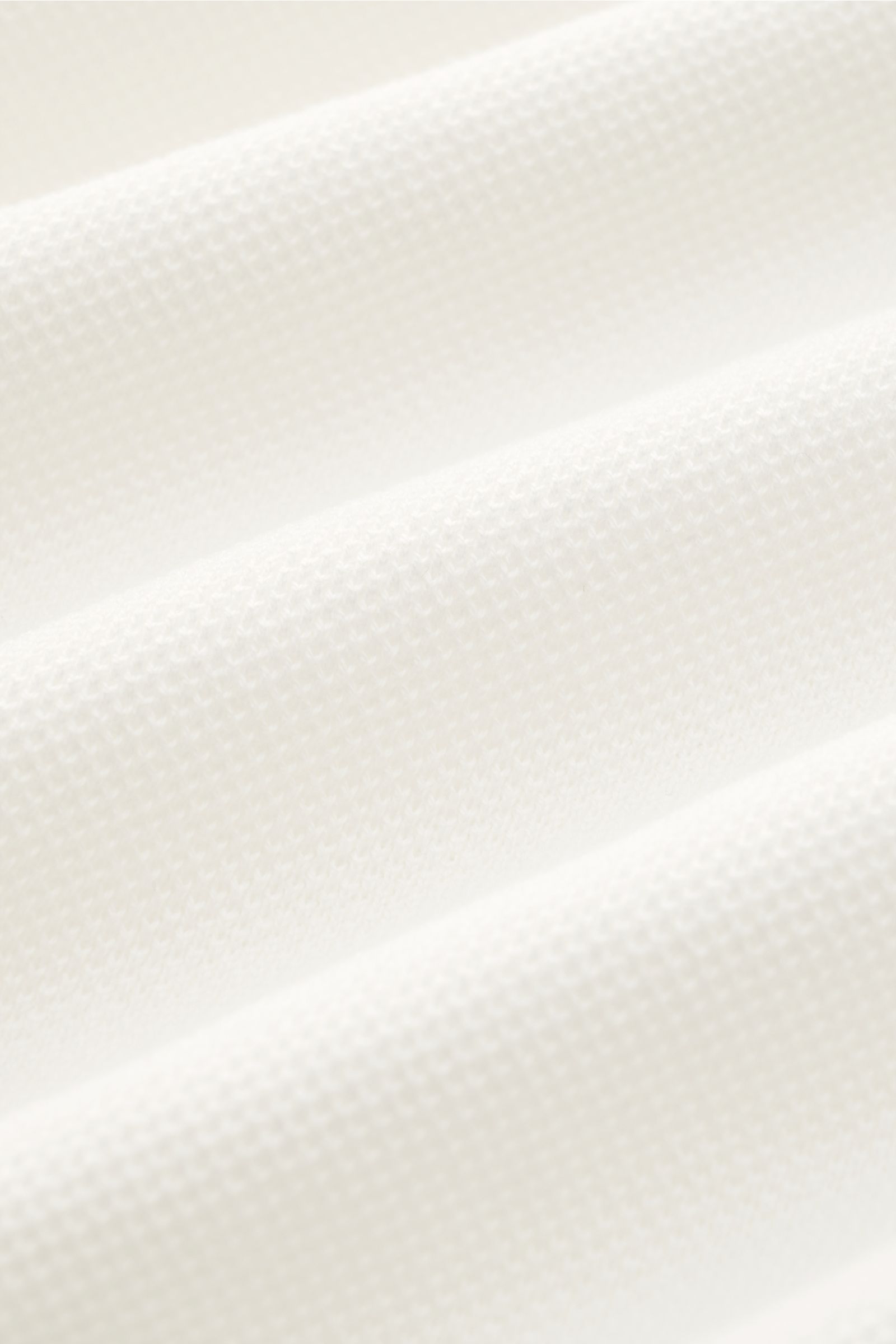 Lardini Kurzarm-Strickpolo offwhite in Slim Fit, feines Piqué, reine Baumwolle, weiche Haptik, Detailaufnahme der Struktur aus schräger Perspektive.