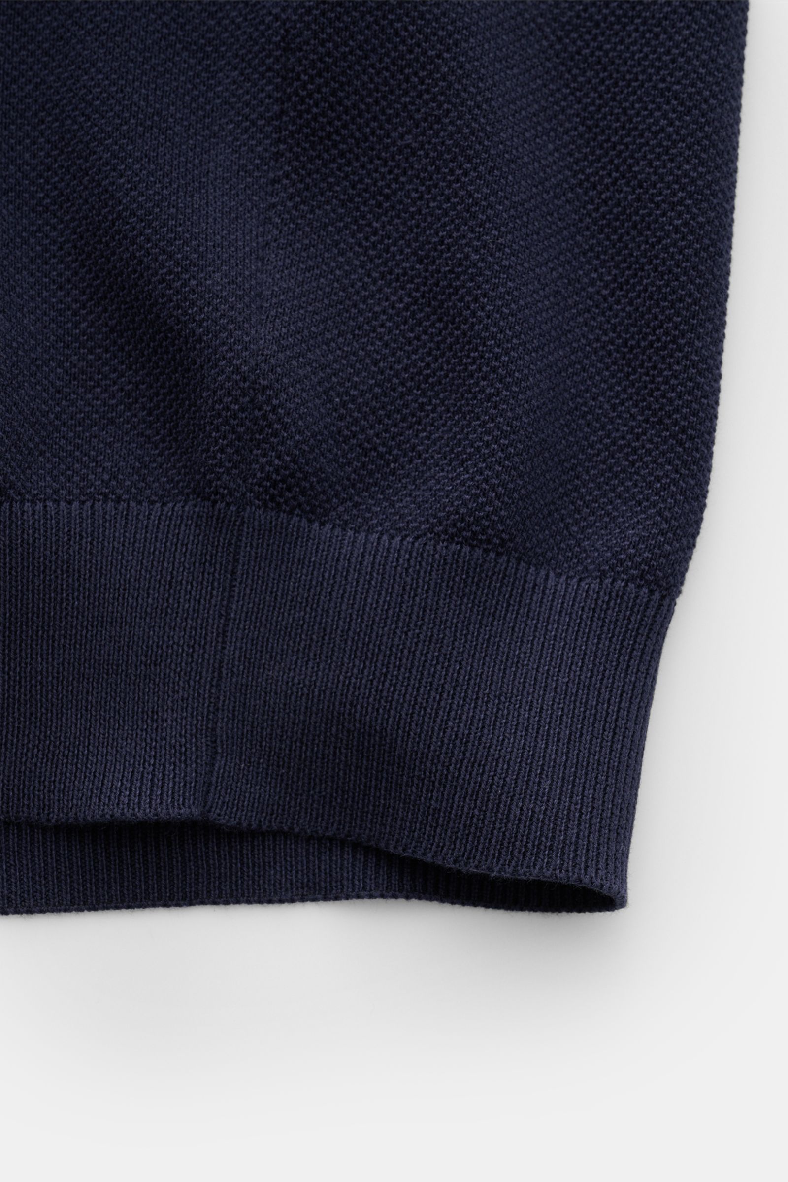 Close-up view of the bottom hem of the Lardini Kurzarm-Strickpolo navy, showing pure cotton fabric with soft grip, fine piqué knit, slim fit, typical polo collar, three-button placket, and flexible ribbed cuffs. Ein Polo, das mehr kann als casual: LARD