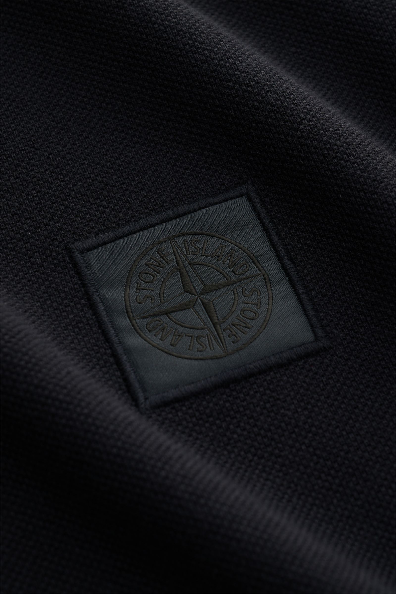 Nahaufnahme des Stone Island Poloshirt 'Ghost Piece' navy aus Baumwoll-Piqué mit tonalem Logo-Label, Slim Fit und körniger Struktur.