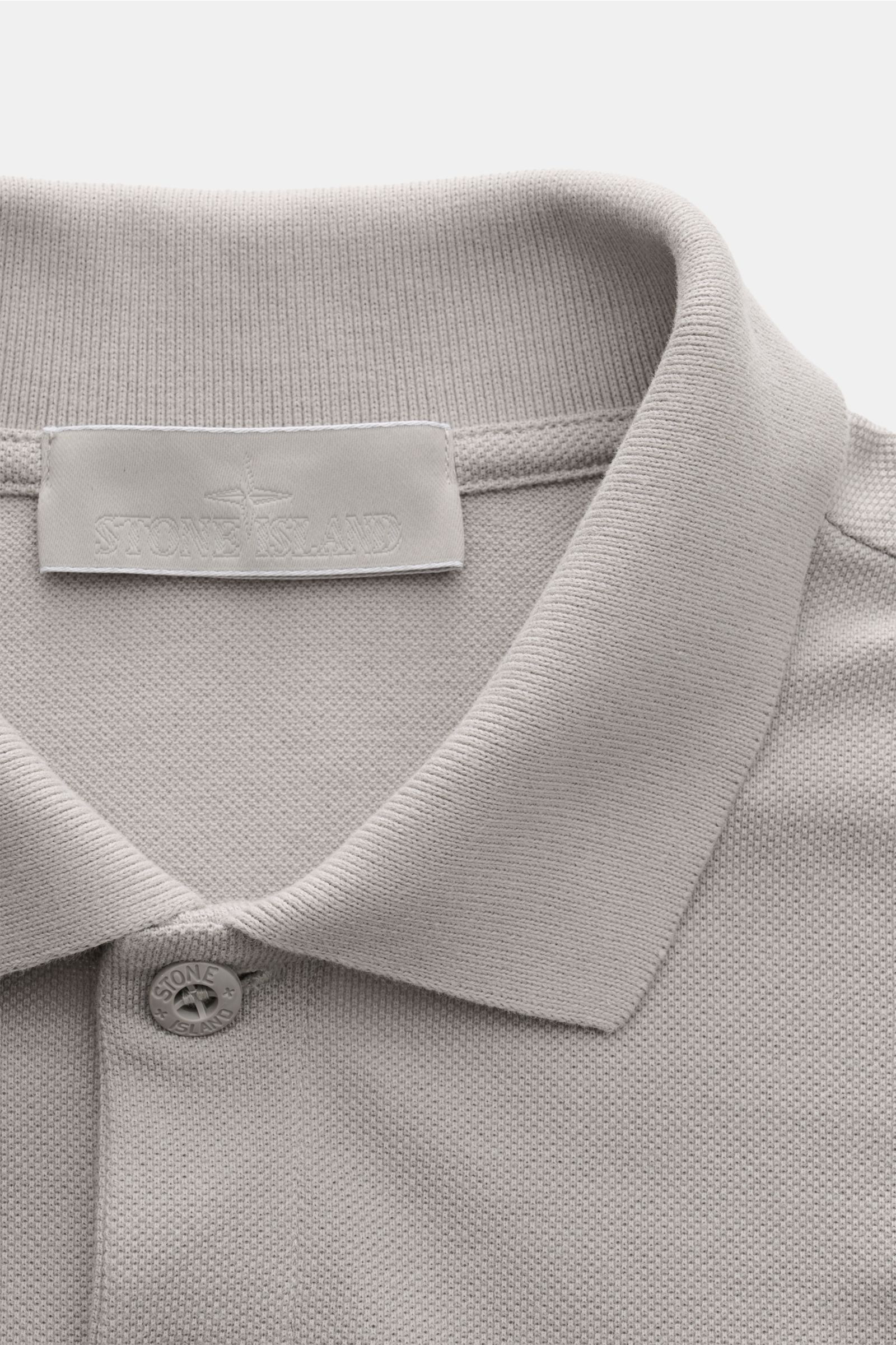 Stone Island Poloshirt 'Ghost Piece' grau, Nahaufnahme von Kragen, zwei-Knopf-Leiste, Baumwoll-Piqué, tonales Weblabel, Slim Fit, seitliche Saumschlitze.