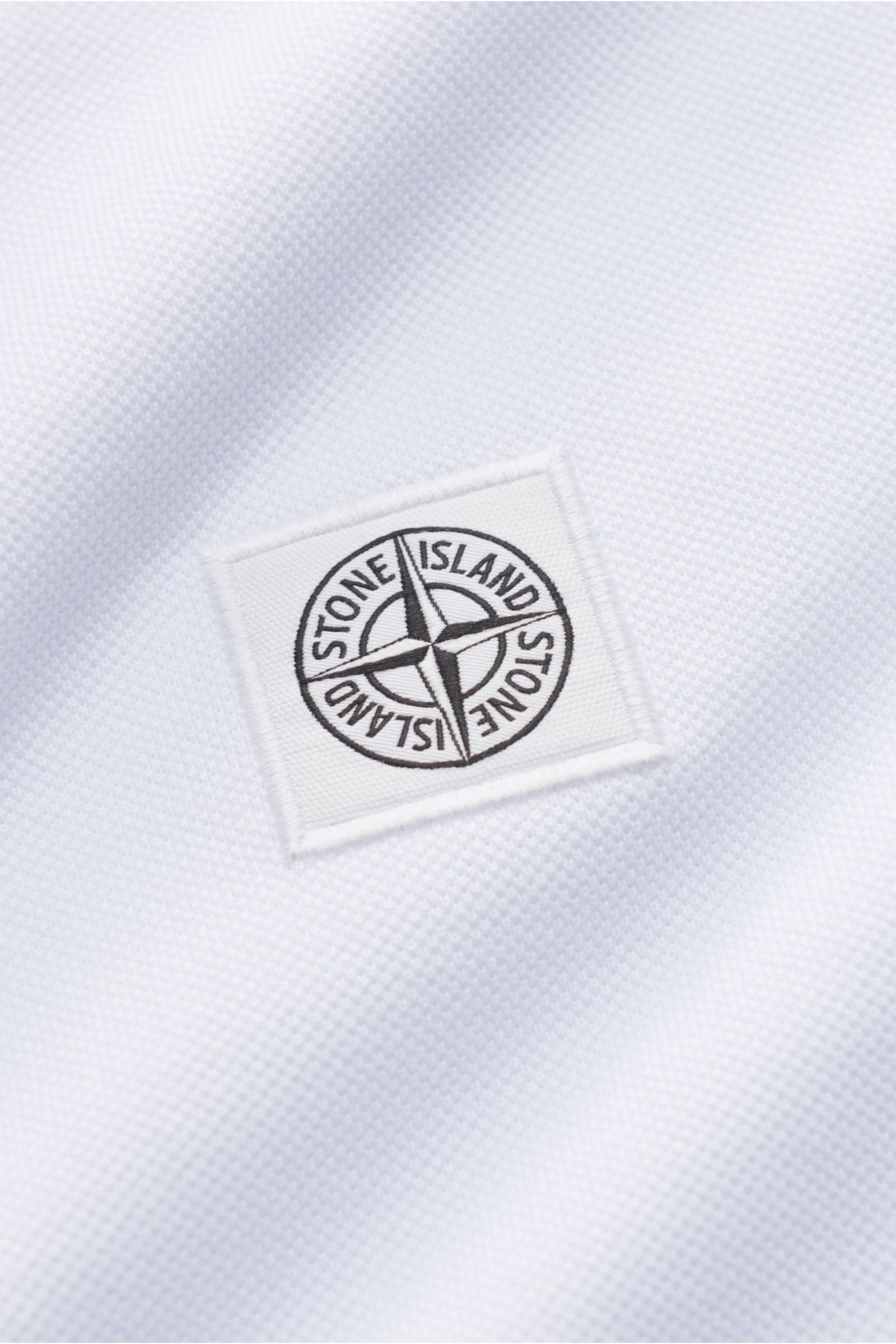 Close-up front view of the Stone Island Poloshirt weiß showing the textured pure cotton piqué fabric and the embroidered STONE ISLAND web label. The classic polo shirt is a must-have in sporty men's wardrobes, made from breathable garment-dyed cotton piqu